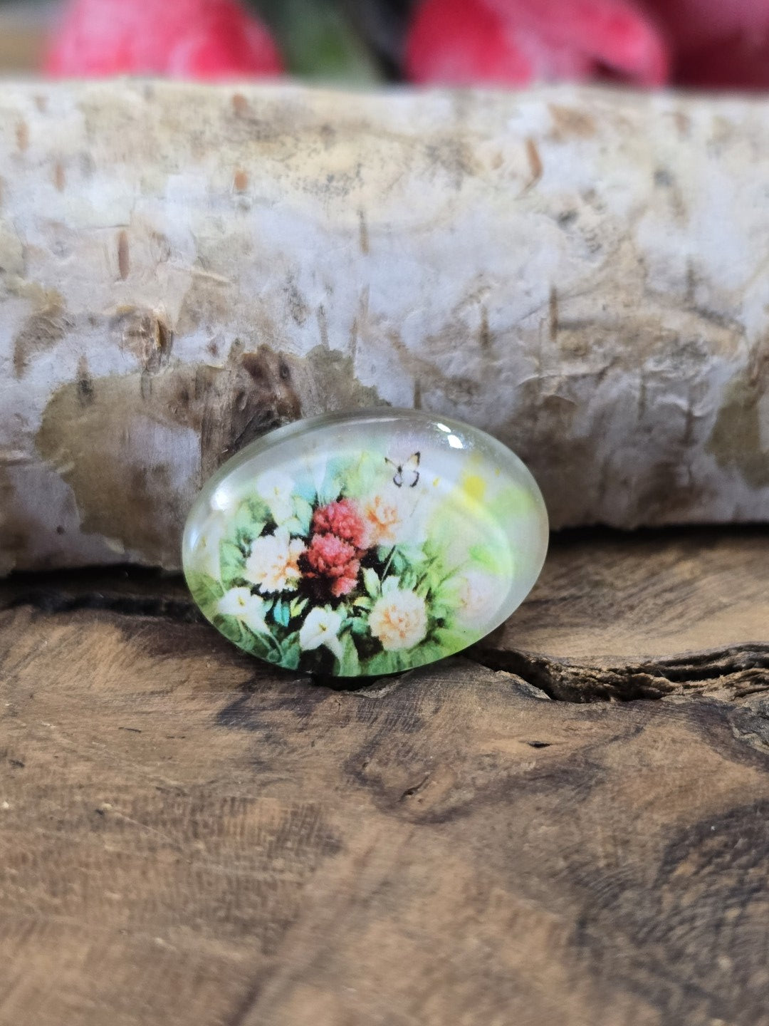 Nahaufnahme eines einzelnen 18x13 mm Glascabochons mit detailreichem Blumenstrauß und Schmetterling als Schmuckzubehör zum Basteln von Ringen, Medaillons oder Ohrringen.
