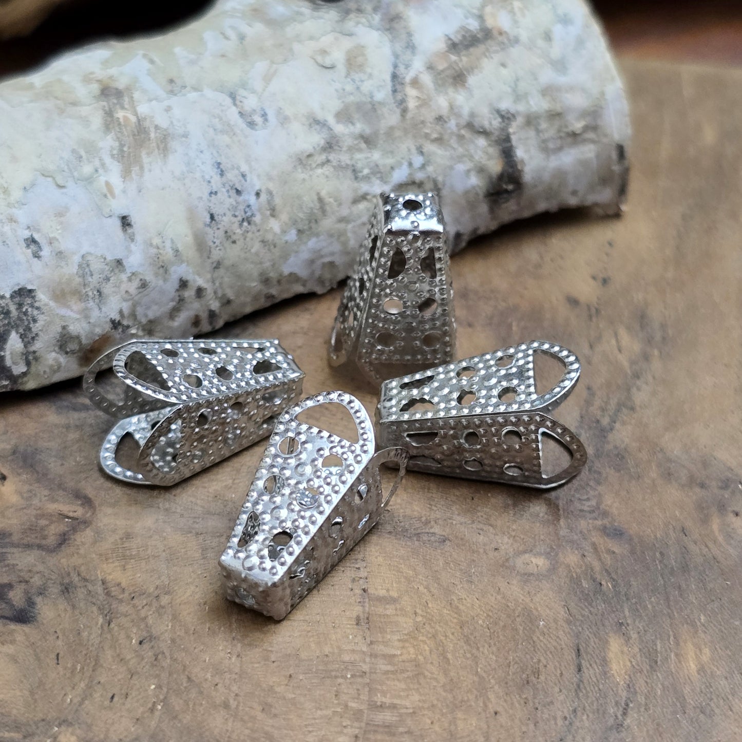 Das Bild zeigt Kappen Bandenden – Rhodiumfarbig | Vielseitig & Elegant ✨
Diese Kappen sind die perfekte Wahl für elegante Schmuck- und DIY-Projekte! Sie eignen sich ideal für breite, weiche Stoffbänder wie Organza, Satin oder Chiffon. Einfach das Bandende raffen, mit einem Perlenfaden umwickeln, durch das Loch in der Kappe fädeln und mit einer Perle oder einem Crimp sichern – schon hast du eine stabile Schlaufe für Verschlüsse oder dekorative Akzente.