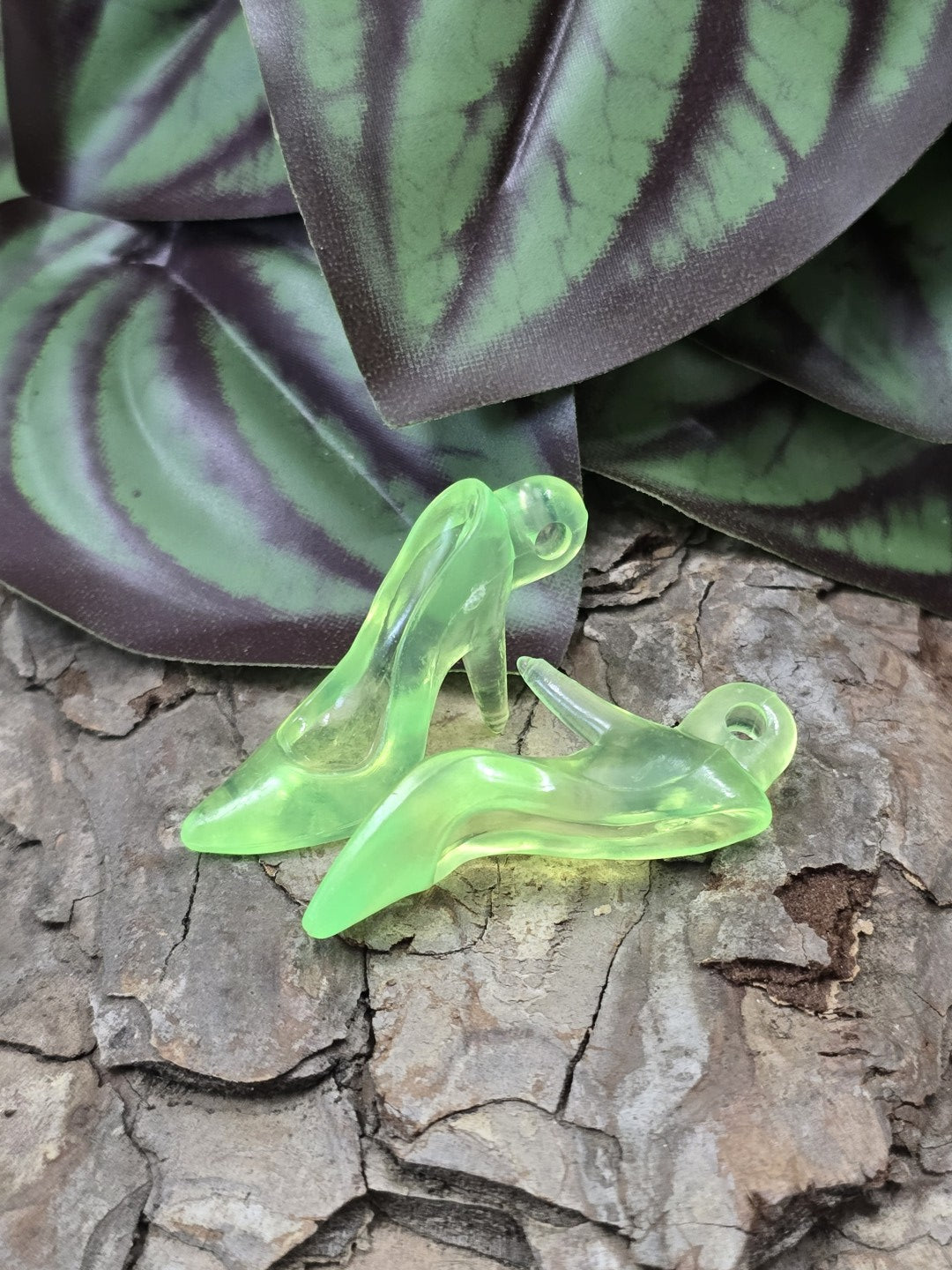 Zwei neongrüne transparente Pumps-Schmuckanhänger aus Acryl auf Rindenuntergrund