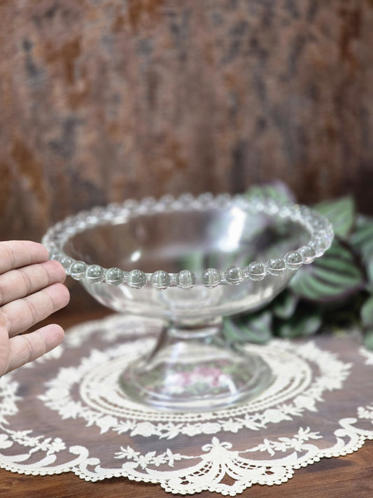 Vintage Pressglas Fußschale mit Perlenrand und Standfuß, von einer Hand als Größenvergleich seitlich gehalten