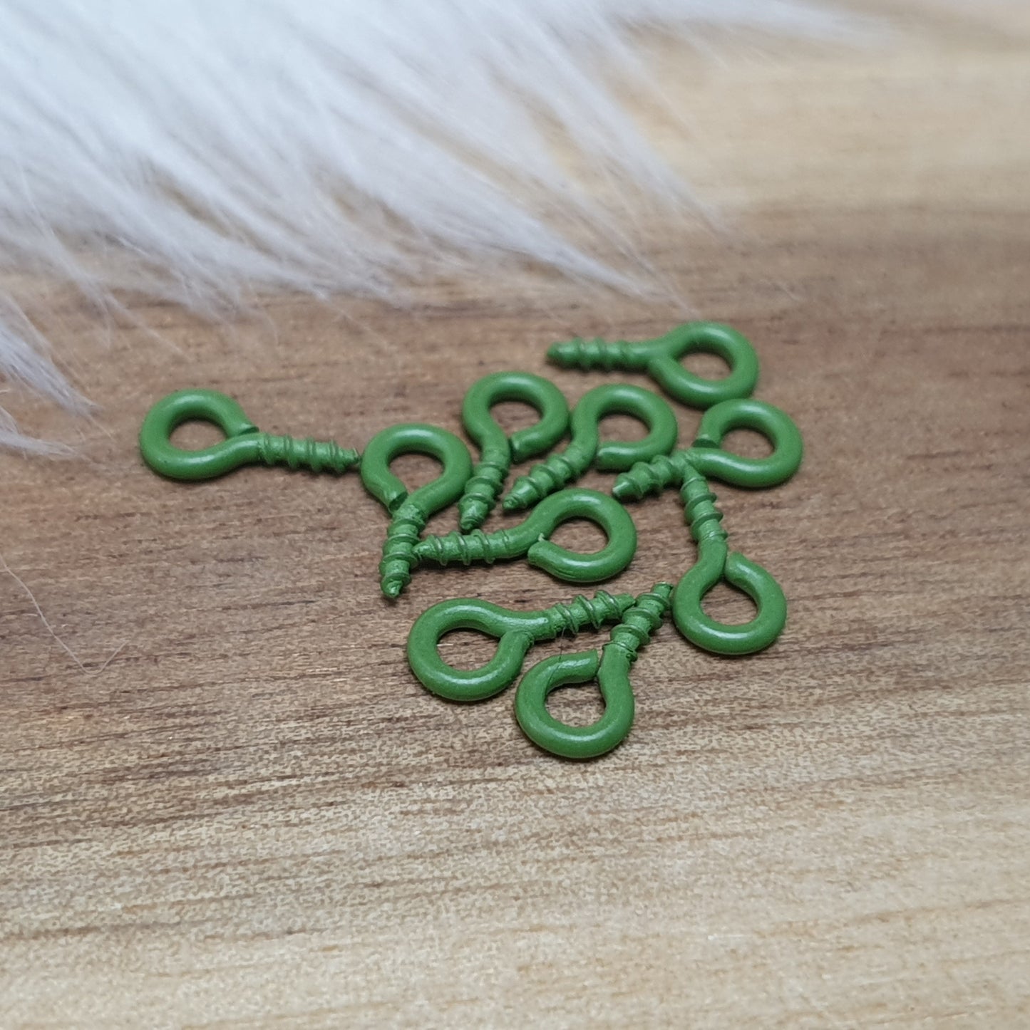 Das Bild zeigt ein Set von 10 farbig lackierten Schraubösen in verschiedenen lebhaften Farben, darunter Hellblau, Grün, Rot, Aqua, Weiß und Rosa. Jede Schrauböse hat die Abmessungen von ca. 8x4mm und ist sorgfältig gestaltet, um eine einfache Anwendung zu ermöglichen. Die Schraubösen sind ideal für das Einschrauben in Materialien wie Holz, Resin oder Acryl, um individuelle Anhänger zu kreieren. Die glänzende Oberfläche der Schraubösen sorgt für einen attraktiven Look, der jedem kreativen Projekt einen farbe