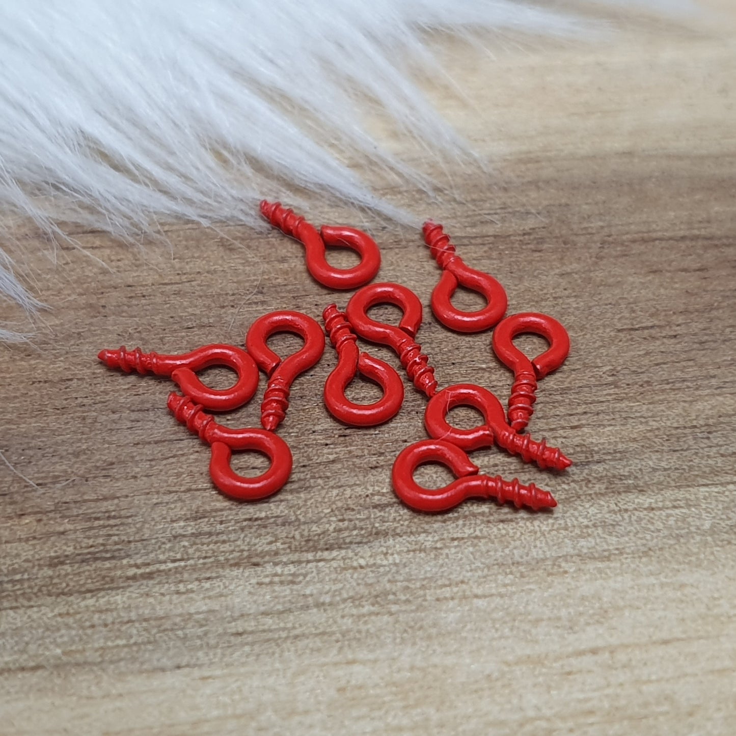 Das Bild zeigt ein Set von 10 farbig lackierten Schraubösen in verschiedenen lebhaften Farben, darunter Hellblau, Grün, Rot, Aqua, Weiß und Rosa. Jede Schrauböse hat die Abmessungen von ca. 8x4mm und ist sorgfältig gestaltet, um eine einfache Anwendung zu ermöglichen. Die Schraubösen sind ideal für das Einschrauben in Materialien wie Holz, Resin oder Acryl, um individuelle Anhänger zu kreieren. Die glänzende Oberfläche der Schraubösen sorgt für einen attraktiven Look, der jedem kreativen Projekt einen farbe