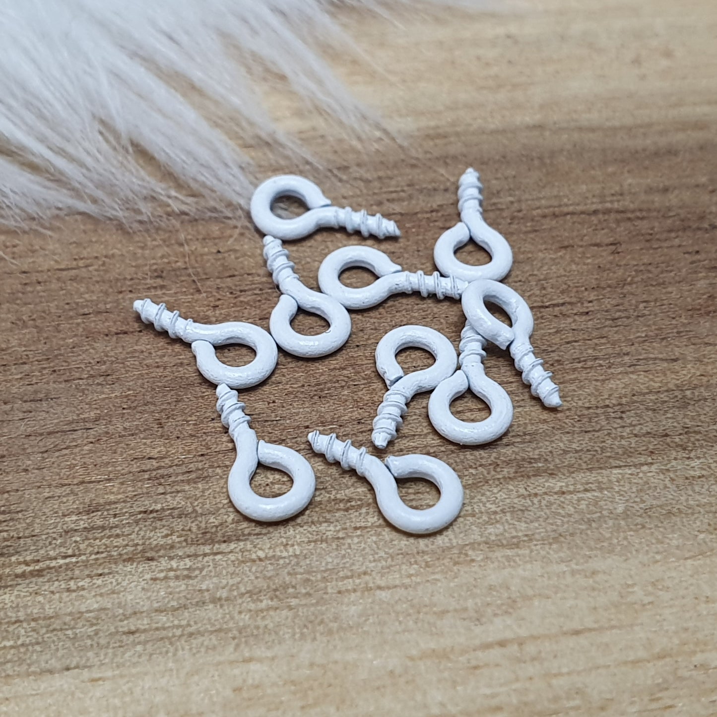 Das Bild zeigt ein Set von 10 farbig lackierten Schraubösen in verschiedenen lebhaften Farben, darunter Hellblau, Grün, Rot, Aqua, Weiß und Rosa. Jede Schrauböse hat die Abmessungen von ca. 8x4mm und ist sorgfältig gestaltet, um eine einfache Anwendung zu ermöglichen. Die Schraubösen sind ideal für das Einschrauben in Materialien wie Holz, Resin oder Acryl, um individuelle Anhänger zu kreieren. Die glänzende Oberfläche der Schraubösen sorgt für einen attraktiven Look, der jedem kreativen Projekt einen farbe