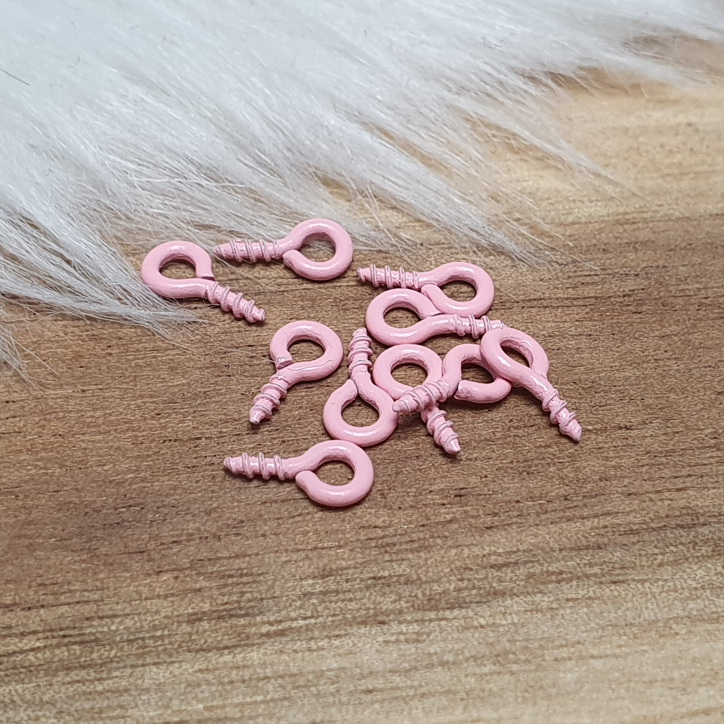 Das Bild zeigt ein Set von 10 farbig lackierten Schraubösen in verschiedenen lebhaften Farben, darunter Hellblau, Grün, Rot, Aqua, Weiß und Rosa. Jede Schrauböse hat die Abmessungen von ca. 8x4mm und ist sorgfältig gestaltet, um eine einfache Anwendung zu ermöglichen. Die Schraubösen sind ideal für das Einschrauben in Materialien wie Holz, Resin oder Acryl, um individuelle Anhänger zu kreieren. Die glänzende Oberfläche der Schraubösen sorgt für einen attraktiven Look, der jedem kreativen Projekt einen farbe