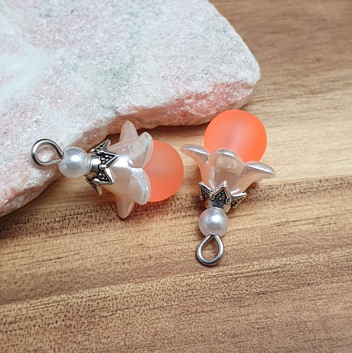 Das Bild zeigt ein 30-teiliges Bastelset zur Schmuckherstellung, ideal für kreative Bastler. In dem Set sind Materialien enthalten, um 6 Blumenanhänger in Orange und Weiß zu gestalten. Zu sehen sind verschiedene Komponenten: matte orangefarbene Glasperlen, cremeweiße Acrylperlen, weiße Blütenkäppchen und antik silberfarbige Sternkäppchen. Alle Teile sind sorgfältig angeordnet, um die Vielseitigkeit und Farbpalette des Sets hervorzuheben. Dieses Set bietet die perfekte Grundlage für die Gestaltung einzigarti