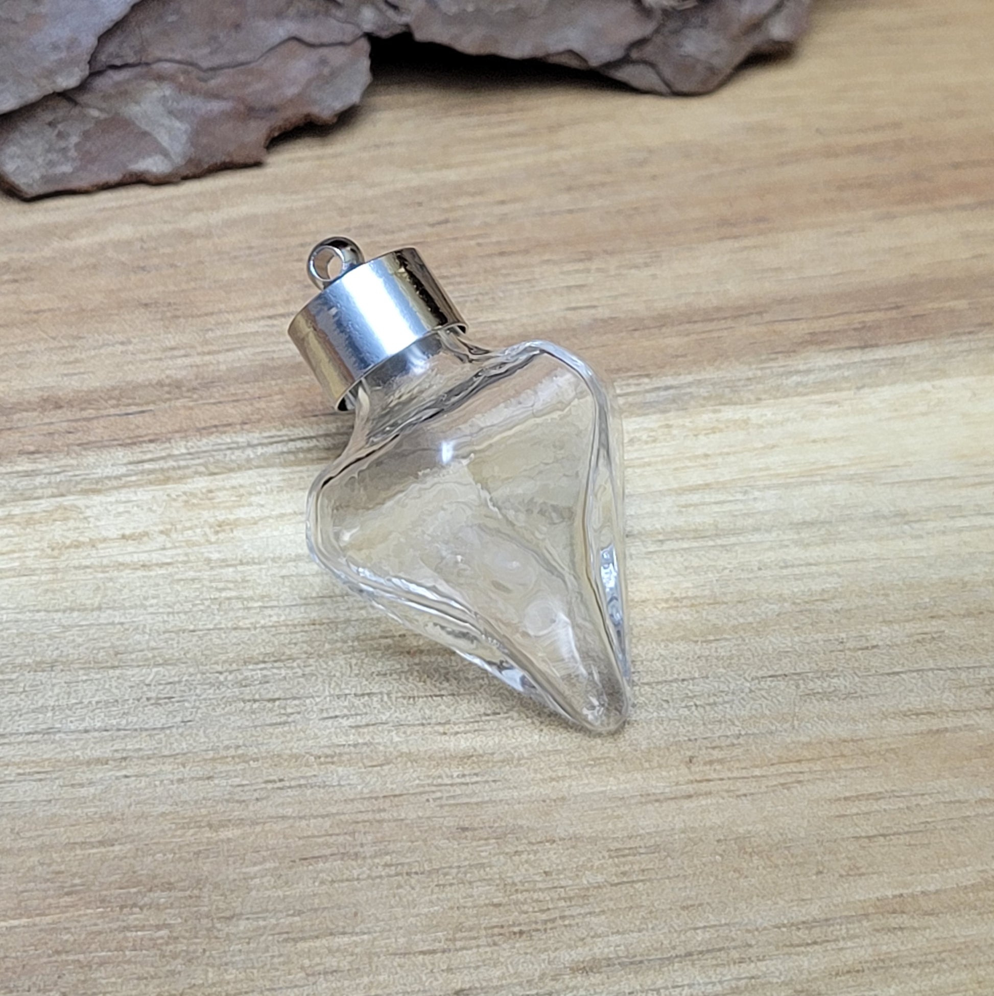 Anhänger Glasflasche in konischer Form, ideal zum befüllen.  Die Glasflasche hat eine nach unten spitz zulaufende Form mit sechs flachen Seiten und einer Öffnung oben. Diese Öffnung bietet Platz für eine Vielzahl von Materialien, darunter Edelsteinsplitter, Sand, Glitzer, Granulat und sogar Flüssigkeiten (bitte beachten Sie die Öffnungsgröße).