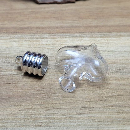Anhänger kleine Glasflasche in Form eines Herzens zum befüllen.  Die Glasflasche hat oben eine Öffnung oben und bietet Platz für eine Vielzahl von Materialien, darunter (wirklich kleine) Edelsteinsplitter, Sand, Glitzer, und Granulat (bitte beachten Sie die Öffnungsgröße). 