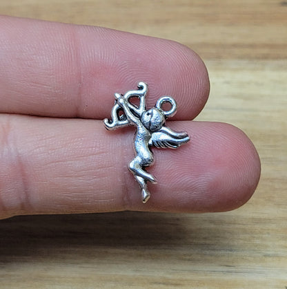 ein kleiner Charms Armor antik silberfarbig liegend auf zwei Fingern zur Größenreferenz