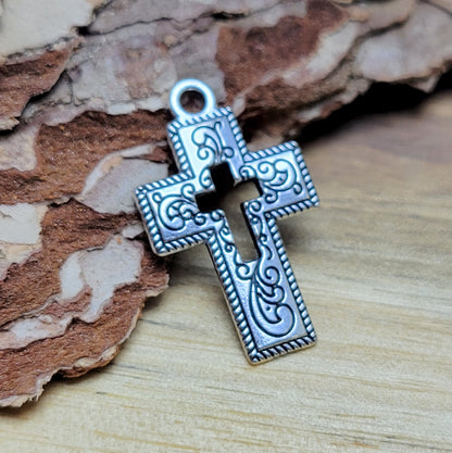 Charmante Kreuz-Anhängern in antik silberfarbiger Ausführung. Mit einer Größe von 23 mm sind sie ideal für Ihre individuelle Schmuckherstellung.  Perfekt für Dirndlschmuck, Taschenschmuck, Ohrschmuck, Armbänder, Ketten & Choker oder Trachtenaccessoires.  Die Kreuz-Anhänger sind mit Verzierungen versehen und einem Kreuz in der Mitte als Cutout.  Ihre beidseitige geprägung macht sie vielseitig in der Verwendung.