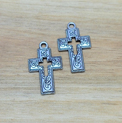 Charmante Kreuz-Anhängern in antik silberfarbiger Ausführung. Mit einer Größe von 23 mm sind sie ideal für Ihre individuelle Schmuckherstellung.  Perfekt für Dirndlschmuck, Taschenschmuck, Ohrschmuck, Armbänder, Ketten & Choker oder Trachtenaccessoires.  Die Kreuz-Anhänger sind mit Verzierungen versehen und einem Kreuz in der Mitte als Cutout.  Ihre beidseitige geprägung macht sie vielseitig in der Verwendung.