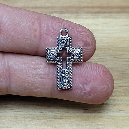 Charmante Kreuz-Anhängern in antik silberfarbiger Ausführung. Mit einer Größe von 23 mm sind sie ideal für Ihre individuelle Schmuckherstellung.  Perfekt für Dirndlschmuck, Taschenschmuck, Ohrschmuck, Armbänder, Ketten & Choker oder Trachtenaccessoires.  Die Kreuz-Anhänger sind mit Verzierungen versehen und einem Kreuz in der Mitte als Cutout.  Ihre beidseitige geprägung macht sie vielseitig in der Verwendung.