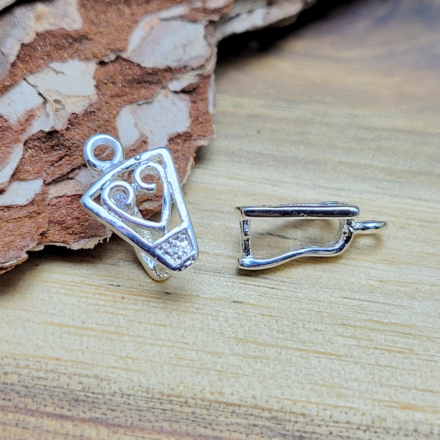 Diese 2 Schnörkel-Anhängerösen sind nicht nur stilvoll, sondern auch äußerst vielseitige Schmuckzubehörteile. Mit ihrer glänzenden .925 Sterling Versilberung werden sie zu edlen Komponenten, die sich perfekt als Aufhängevorrichtungen für Schmuckstücke und Edelsteine eignen.