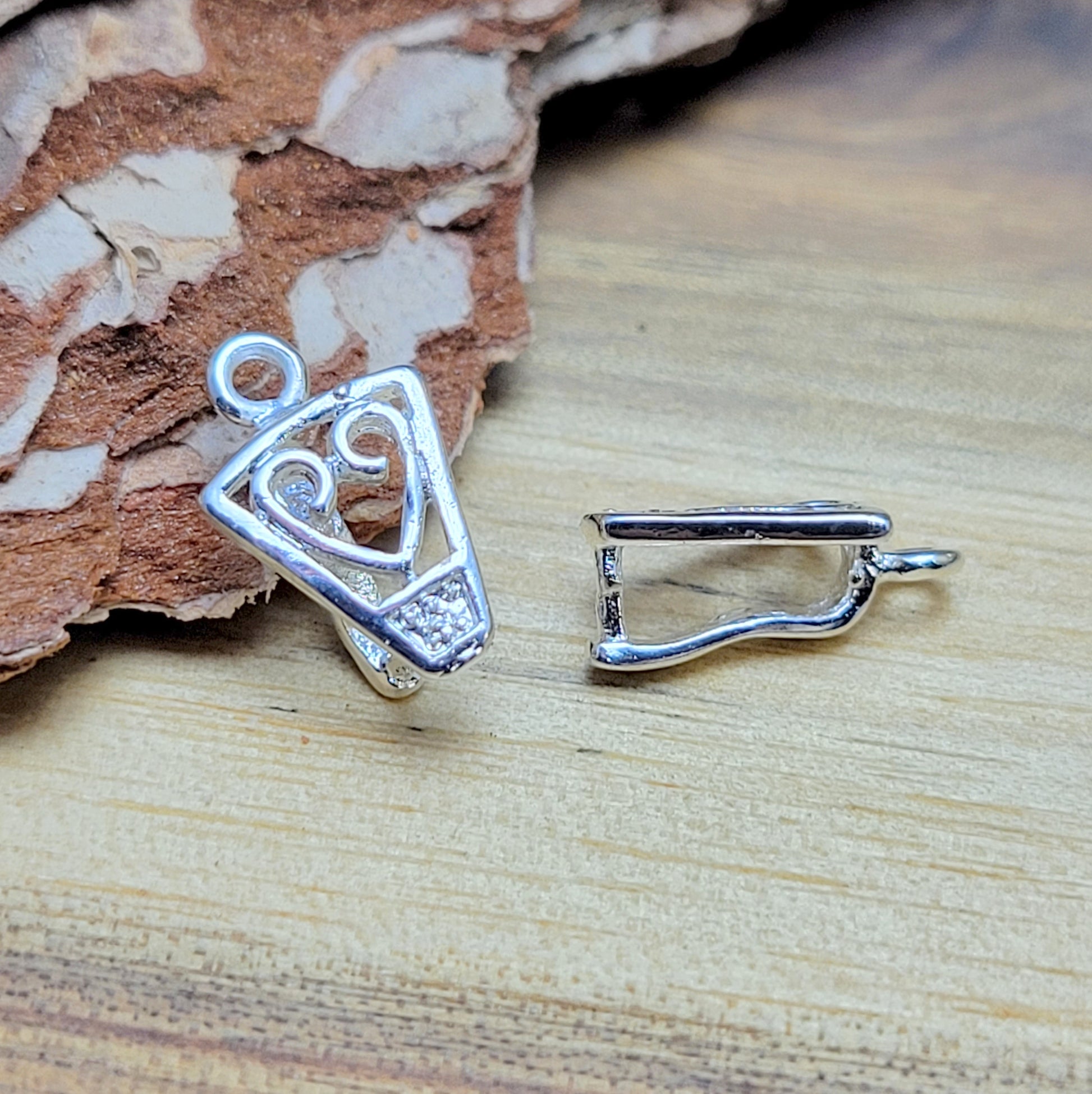 Diese 2 Schnörkel-Anhängerösen sind nicht nur stilvoll, sondern auch äußerst vielseitige Schmuckzubehörteile. Mit ihrer glänzenden .925 Sterling Versilberung werden sie zu edlen Komponenten, die sich perfekt als Aufhängevorrichtungen für Schmuckstücke und Edelsteine eignen.