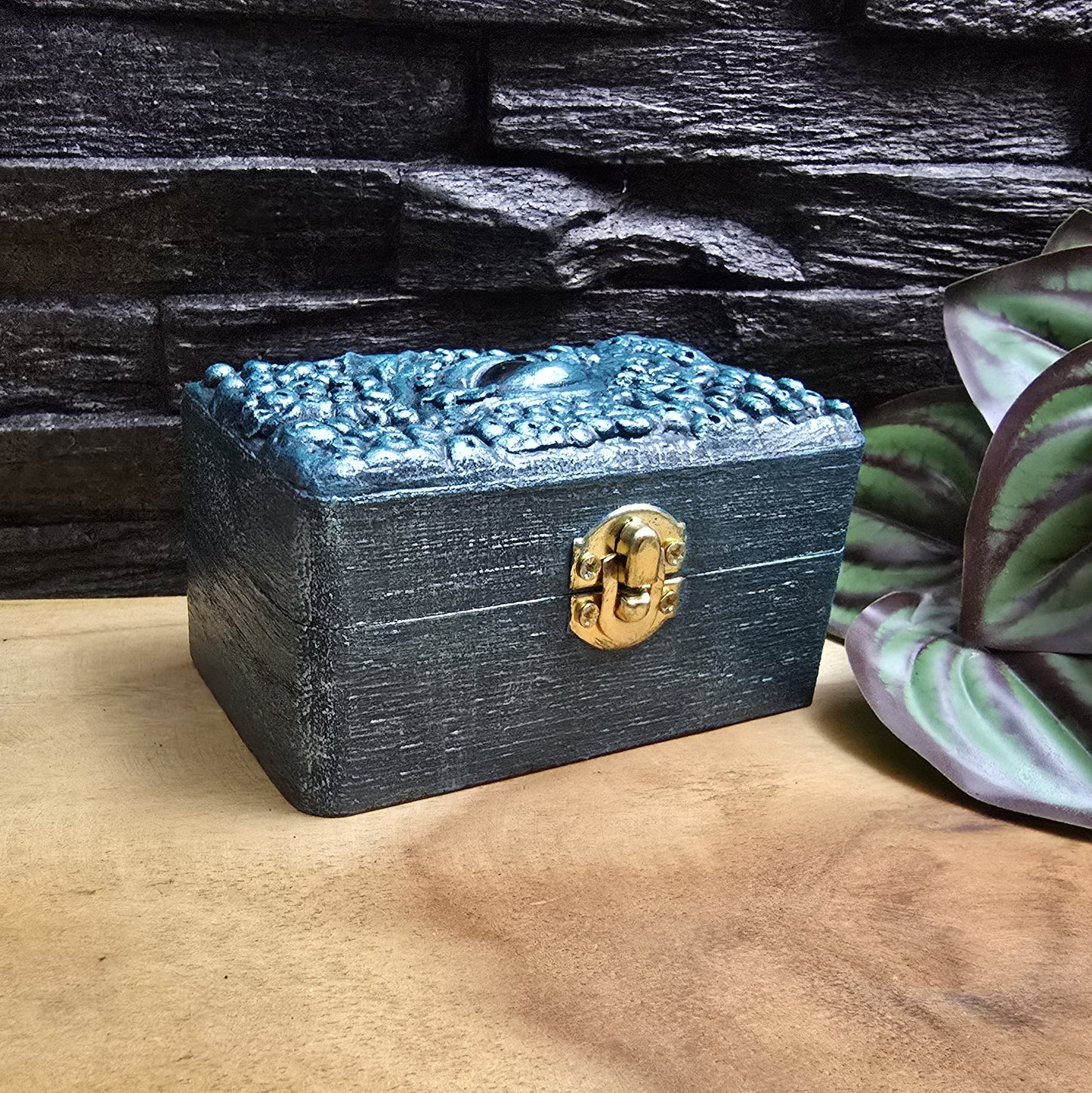 Das Bild zeigt eine geheimnisvolle Schatulle Auge des Oktopus, Meeresgrün, mit Samtkissen und Schnappverschluss. Ladetruhe, Würfelbox, Schmuckkiste

Ob als Schmuckschatulle, Ladebox, Würfelbox oder für andere Kostbarkeiten – diese einzigartige Truhe ist nicht nur ein praktisches Behältnis, sondern ein magisches Artefakt, das die Geschichten der Meere in sich trägt.