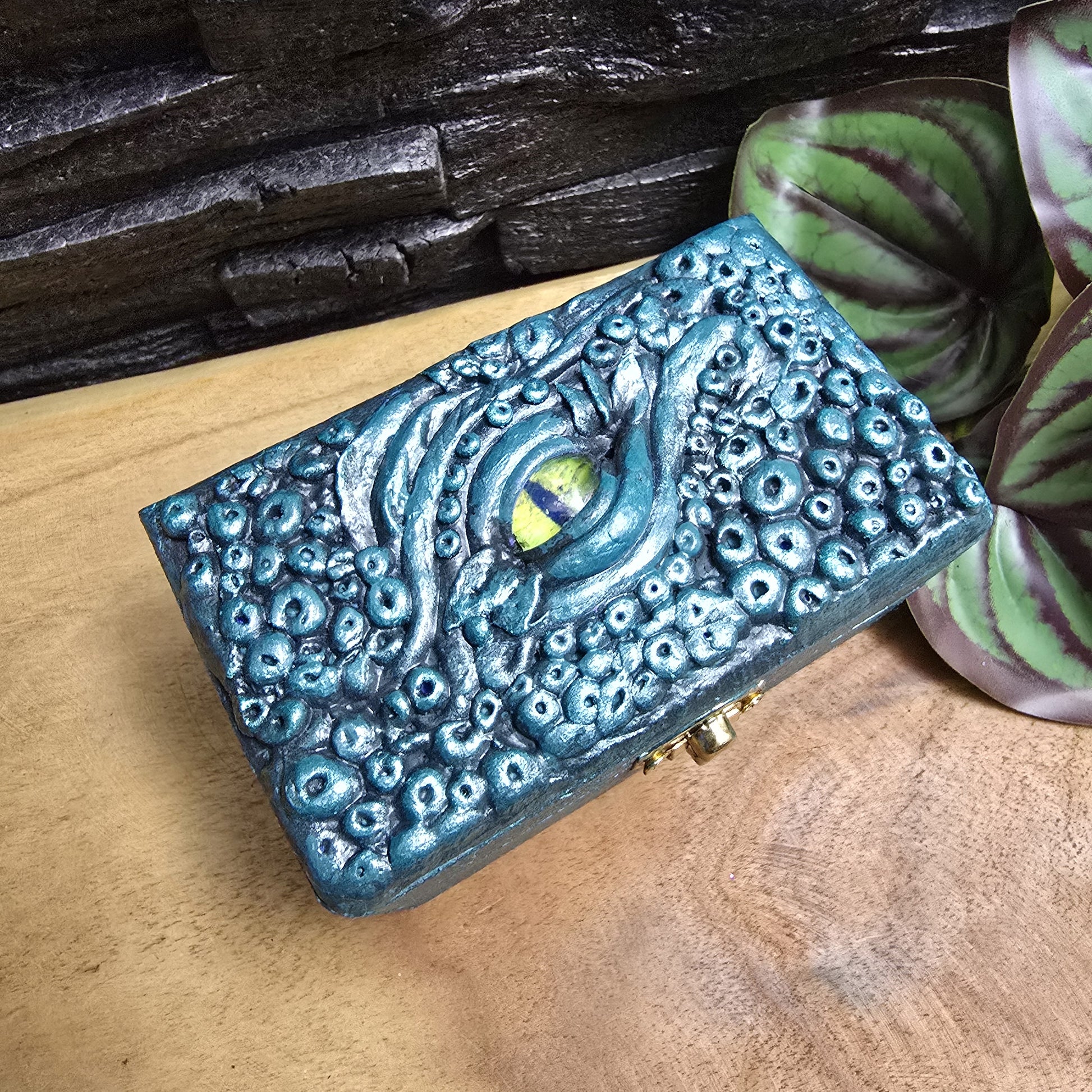 Das Bild zeigt eine geheimnisvolle Schatulle Auge des Oktopus, Meeresgrün, mit Samtkissen und Schnappverschluss. Ladetruhe, Würfelbox, Schmuckkiste

Ob als Schmuckschatulle, Ladebox, Würfelbox oder für andere Kostbarkeiten – diese einzigartige Truhe ist nicht nur ein praktisches Behältnis, sondern ein magisches Artefakt, das die Geschichten der Meere in sich trägt.