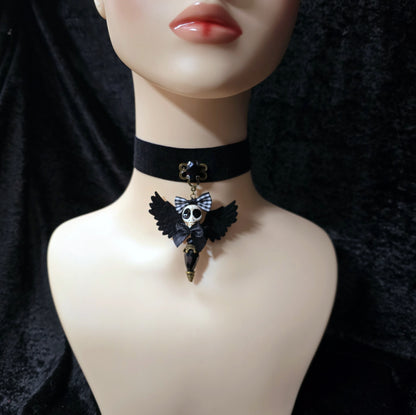 Das Bild zeigt einen einzigartigen Choker, mit einem handgefertigten Anhänger, dem „Ángel de la Muerte“ gestaltet, verbindet kunstvolle Handarbeit mit einer unverkennbaren Ästhetik, die Blicke fesselt. Das zentrale Element dieses Schmuckstücks ist ein der der Todesengel (Muerta).