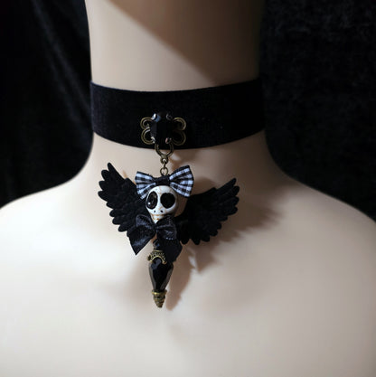 Das Bild zeigt einen einzigartigen Choker, mit einem handgefertigten Anhänger, dem „Ángel de la Muerte“ gestaltet, verbindet kunstvolle Handarbeit mit einer unverkennbaren Ästhetik, die Blicke fesselt. Das zentrale Element dieses Schmuckstücks ist ein der der Todesengel (Muerta).