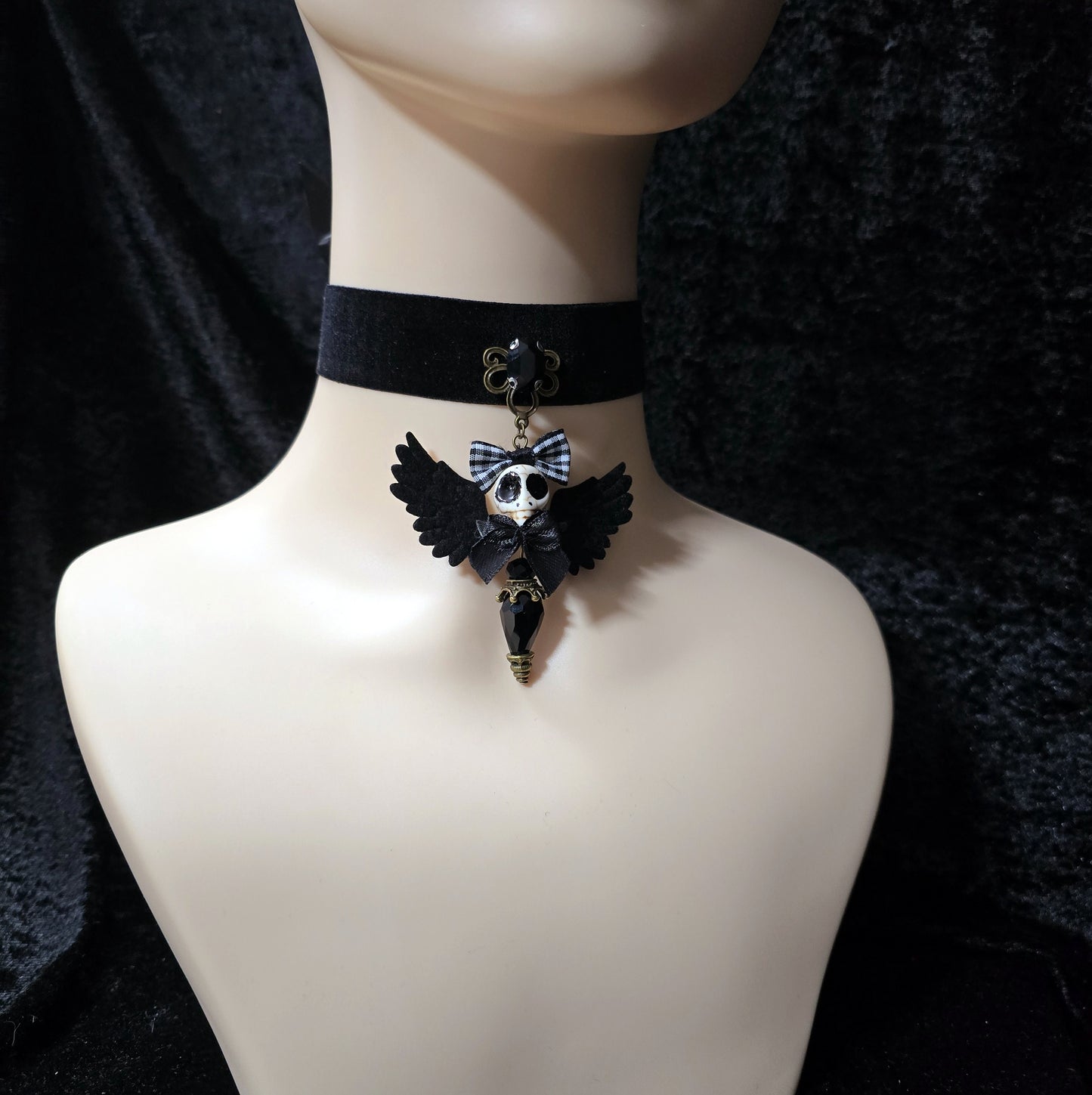 Das Bild zeigt einen einzigartigen Choker, mit einem handgefertigten Anhänger, dem „Ángel de la Muerte“ gestaltet, verbindet kunstvolle Handarbeit mit einer unverkennbaren Ästhetik, die Blicke fesselt. Das zentrale Element dieses Schmuckstücks ist ein der der Todesengel (Muerta).