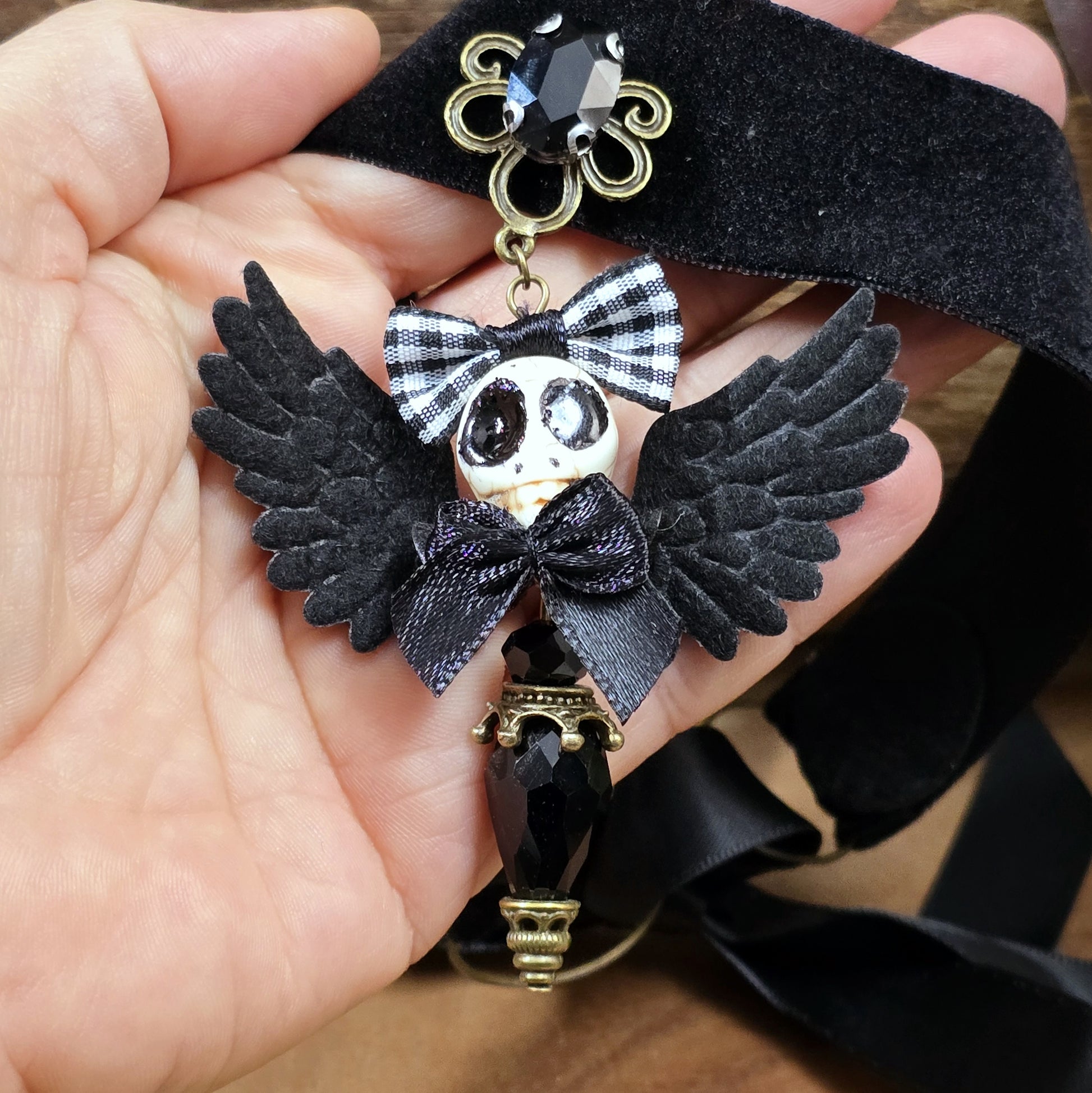 Das Bild zeigt einen einzigartigen Choker, mit einem handgefertigten Anhänger, dem „Ángel de la Muerte“ gestaltet, verbindet kunstvolle Handarbeit mit einer unverkennbaren Ästhetik, die Blicke fesselt. Das zentrale Element dieses Schmuckstücks ist ein der der Todesengel (Muerta).