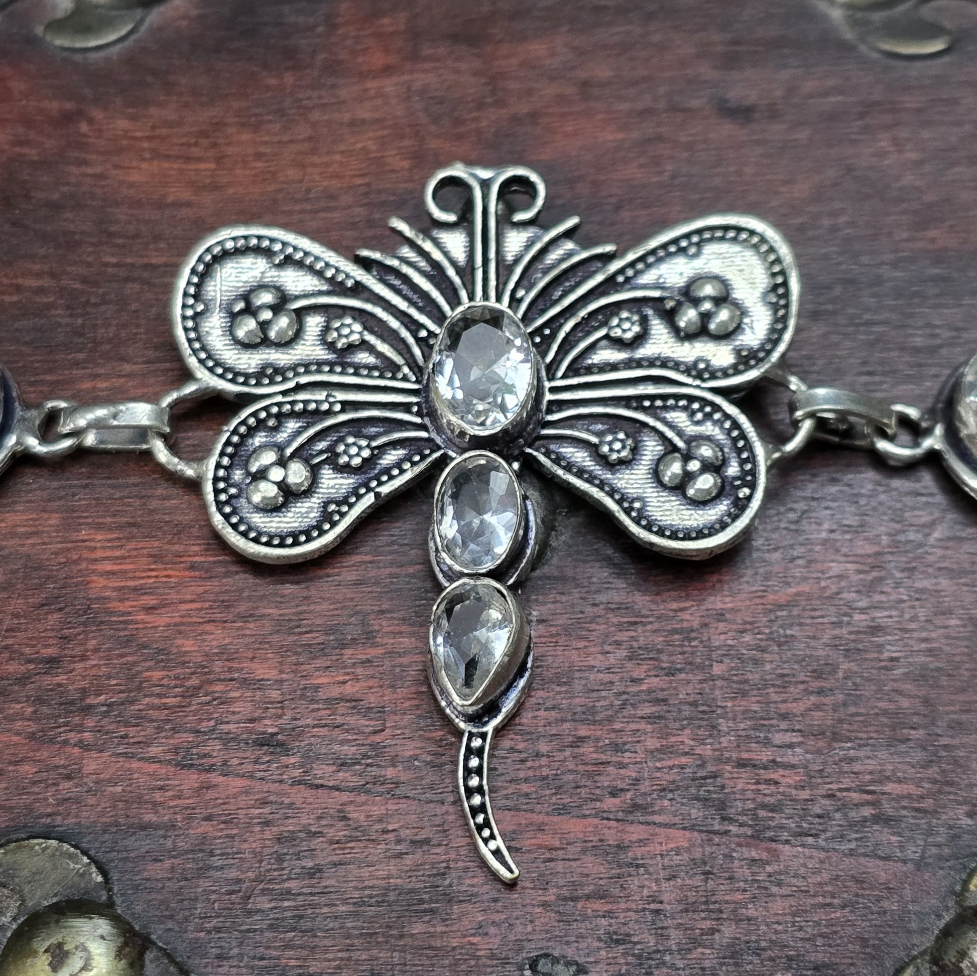 Nahaufnahme eines Armbands aus .925 Silber mit einer filigranen Libelle und Zirkoniasteinen, versehen mit einem Toggle-Verschluss, ca. 4,9 x 4,2 cm Länge.