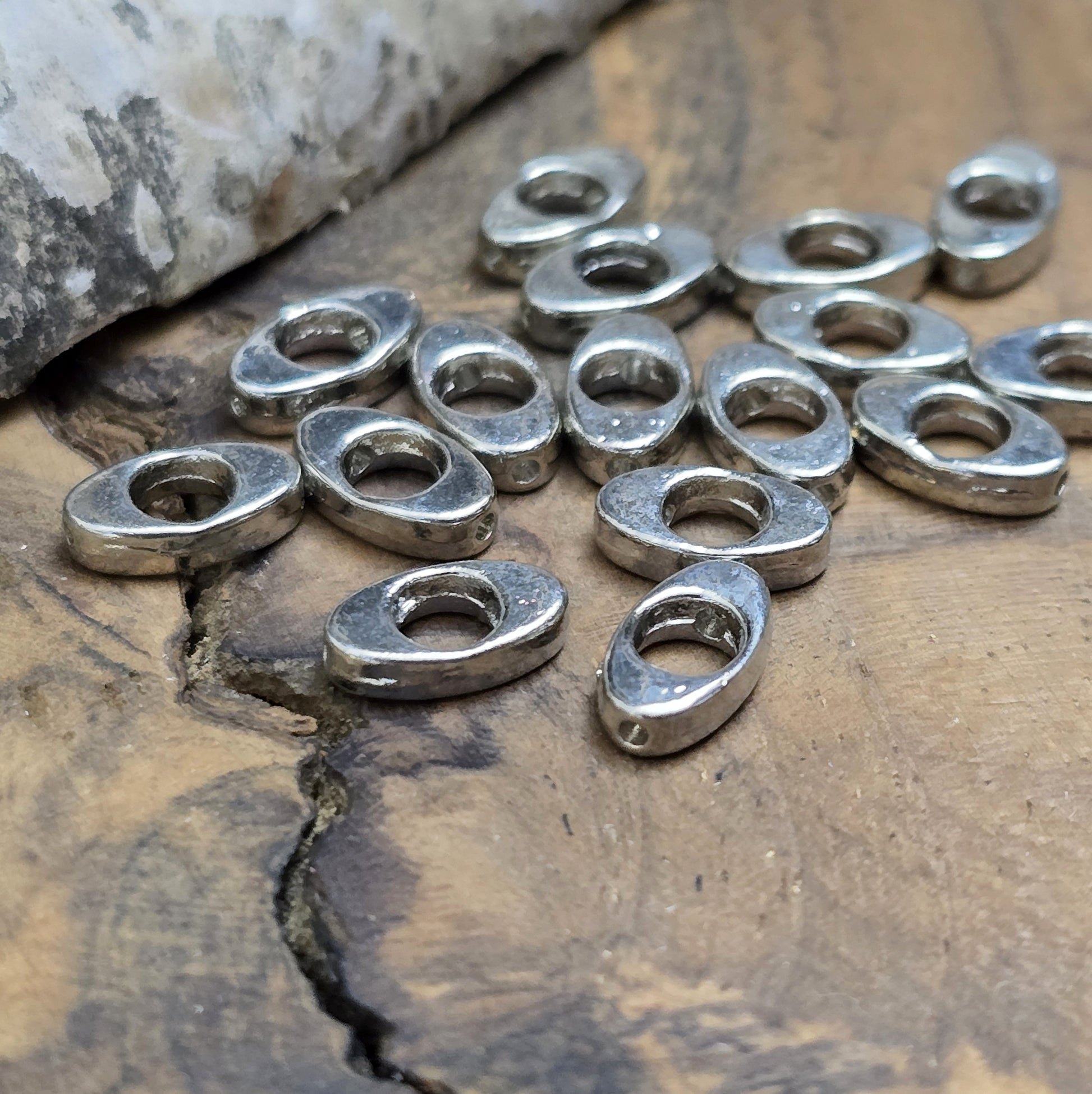 16 schöne ovale Metallperlen in Antiksilber, Augenform, 10mm. Die Perlen haben einen runden Ausschnitt in der Mitte und ein längs verlaufendes Fädelloch. Sie eignen sich hervorragend als Abstandhalter oder für dezente Akzente in Armbändern, Ketten und Ohrschmuck. Menge: 16 Stück.