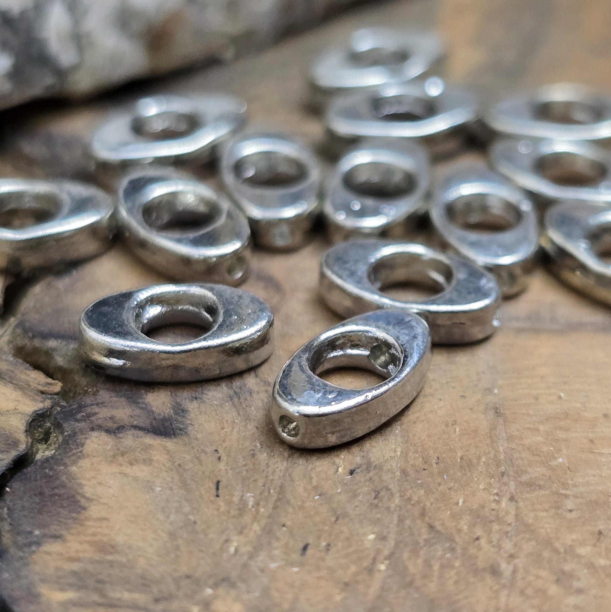 16 schöne ovale Metallperlen in Antiksilber, Augenform, 10mm. Die Perlen haben einen runden Ausschnitt in der Mitte und ein längs verlaufendes Fädelloch. Sie eignen sich hervorragend als Abstandhalter oder für dezente Akzente in Armbändern, Ketten und Ohrschmuck. Menge: 16 Stück.