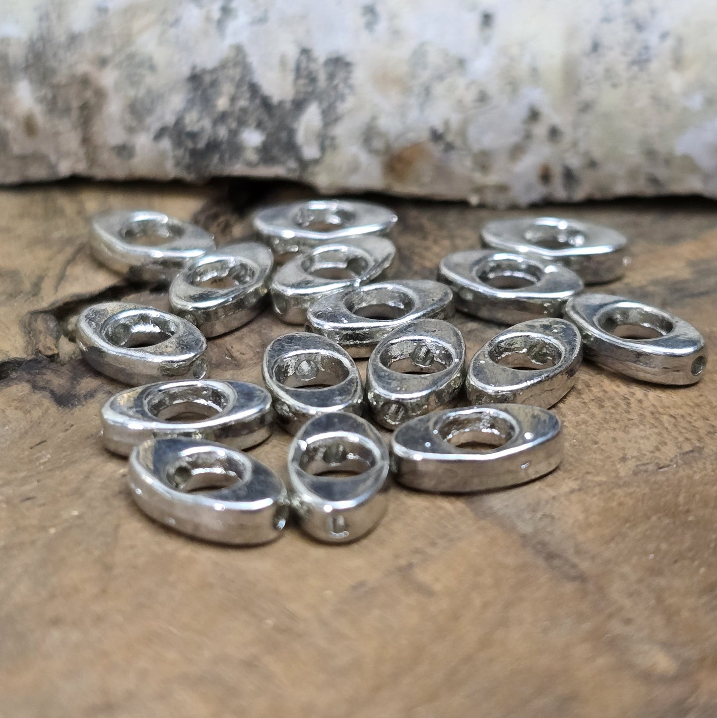 16 schöne ovale Metallperlen in Antiksilber, Augenform, 10mm. Die Perlen haben einen runden Ausschnitt in der Mitte und ein längs verlaufendes Fädelloch. Sie eignen sich hervorragend als Abstandhalter oder für dezente Akzente in Armbändern, Ketten und Ohrschmuck. Menge: 16 Stück.