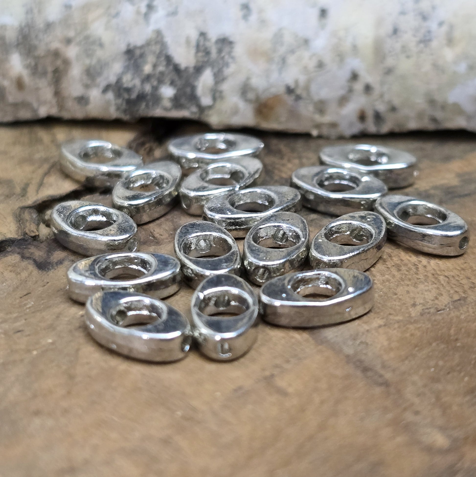 16 schöne ovale Metallperlen in Antiksilber, Augenform, 10mm. Die Perlen haben einen runden Ausschnitt in der Mitte und ein längs verlaufendes Fädelloch. Sie eignen sich hervorragend als Abstandhalter oder für dezente Akzente in Armbändern, Ketten und Ohrschmuck. Menge: 16 Stück.