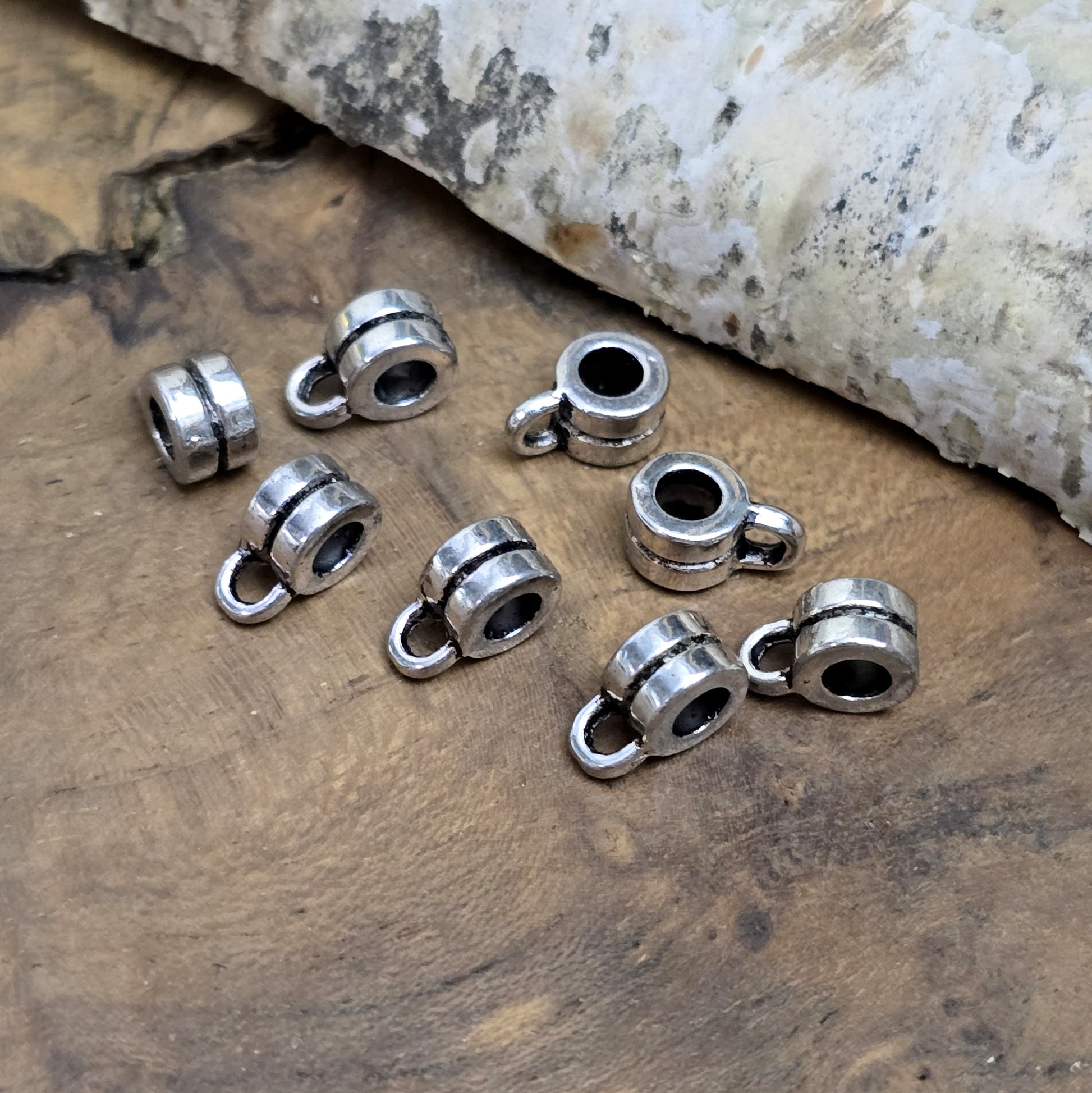 Das Bild zeigt antiksilberfarbene Metallperlen mit Öse. Sie sind eine ideale Ergänzung für kreative Schmuckprojekte. Dank des großzügigen 3-mm-Lochs lassen sie sich mühelos auf verschiedene Bänder und Kordeln auffädeln. Die zusätzliche Öse eröffnet zahlreiche Designmöglichkeiten, um Schmuckstücke individuell zu gestalten.