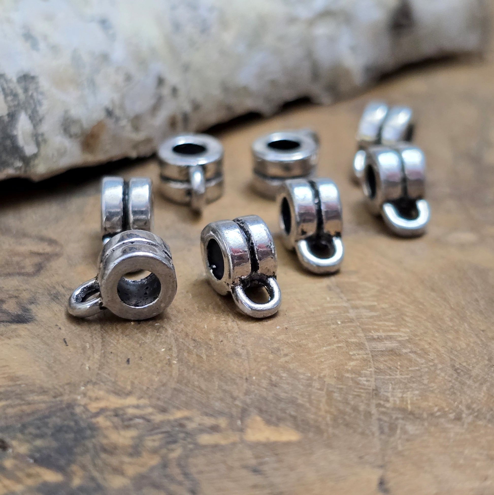 Das Bild zeigt antiksilberfarbene Metallperlen mit Öse. Sie sind eine ideale Ergänzung für kreative Schmuckprojekte. Dank des großzügigen 3-mm-Lochs lassen sie sich mühelos auf verschiedene Bänder und Kordeln auffädeln. Die zusätzliche Öse eröffnet zahlreiche Designmöglichkeiten, um Schmuckstücke individuell zu gestalten.