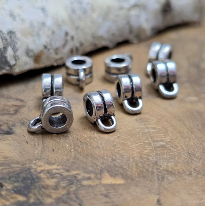Das Bild zeigt antiksilberfarbene Metallperlen mit Öse. Sie sind eine ideale Ergänzung für kreative Schmuckprojekte. Dank des großzügigen 3-mm-Lochs lassen sie sich mühelos auf verschiedene Bänder und Kordeln auffädeln. Die zusätzliche Öse eröffnet zahlreiche Designmöglichkeiten, um Schmuckstücke individuell zu gestalten.