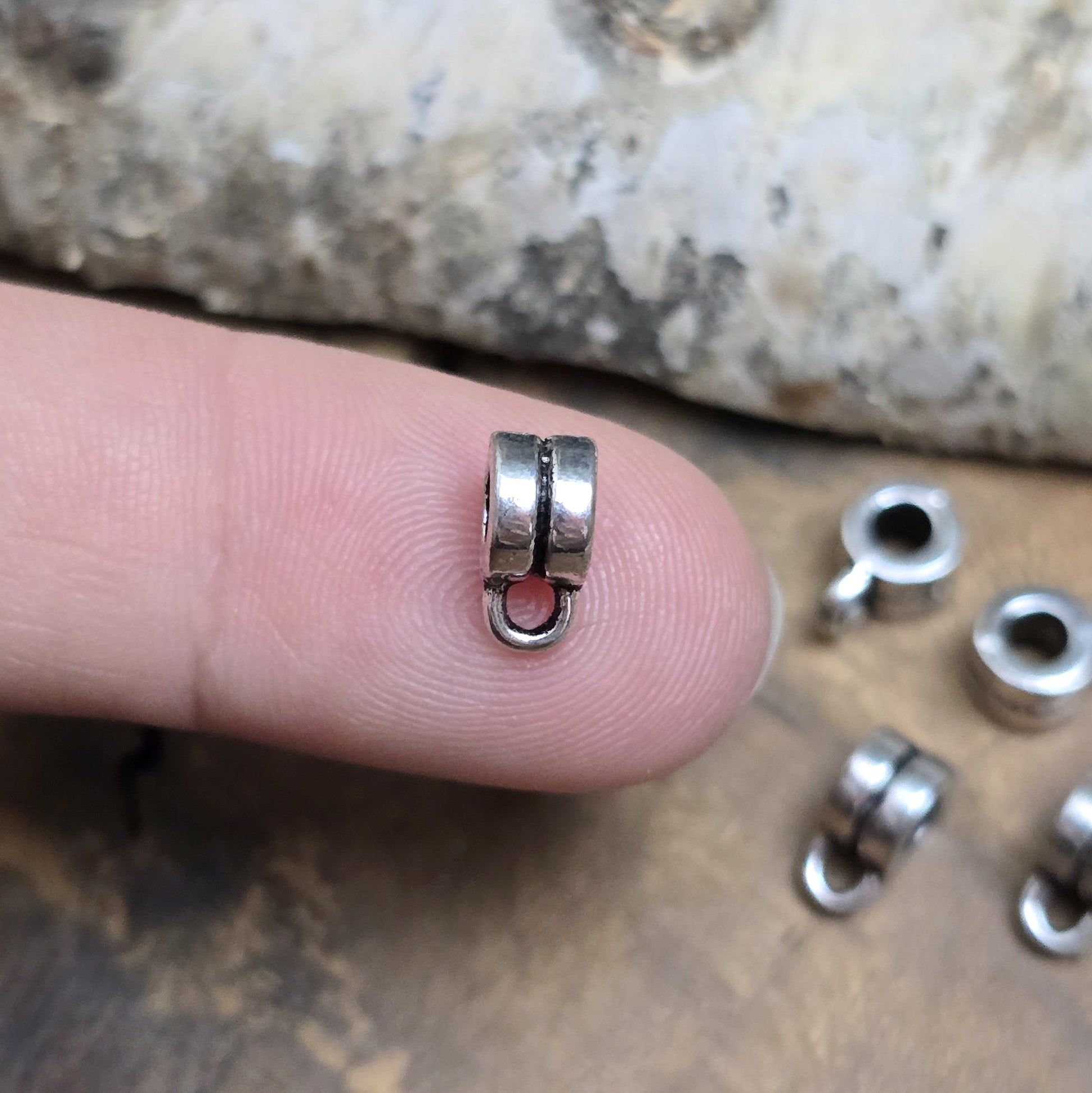 Das Bild zeigt antiksilberfarbene Metallperlen mit Öse. Sie sind eine ideale Ergänzung für kreative Schmuckprojekte. Dank des großzügigen 3-mm-Lochs lassen sie sich mühelos auf verschiedene Bänder und Kordeln auffädeln. Die zusätzliche Öse eröffnet zahlreiche Designmöglichkeiten, um Schmuckstücke individuell zu gestalten.