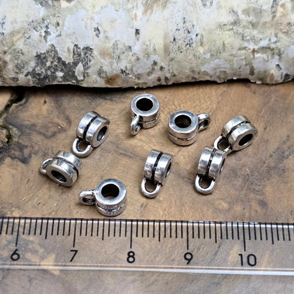 Das Bild zeigt antiksilberfarbene Metallperlen mit Öse. Sie sind eine ideale Ergänzung für kreative Schmuckprojekte. Dank des großzügigen 3-mm-Lochs lassen sie sich mühelos auf verschiedene Bänder und Kordeln auffädeln. Die zusätzliche Öse eröffnet zahlreiche Designmöglichkeiten, um Schmuckstücke individuell zu gestalten.