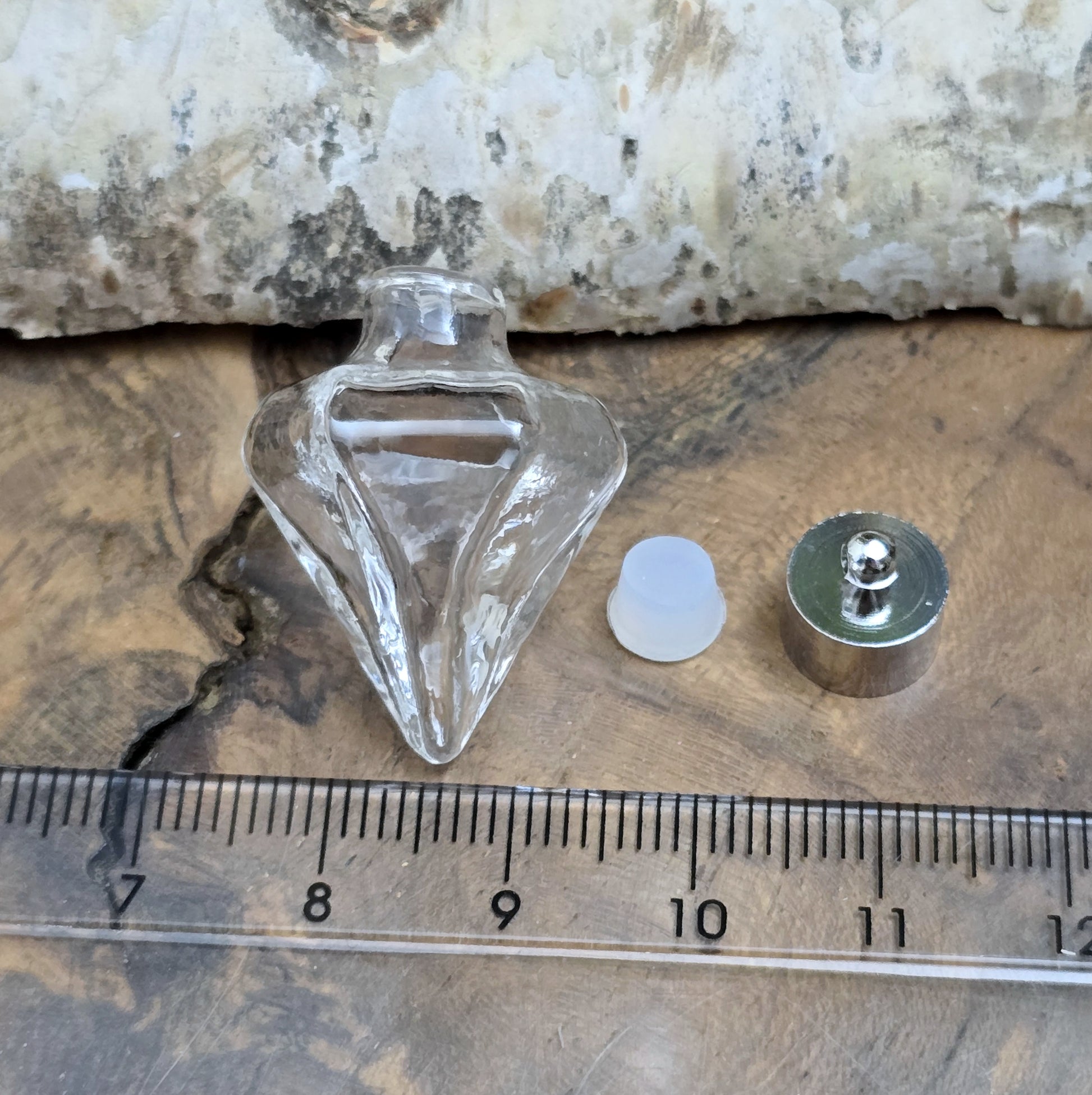 Anhänger Glasflasche in konischer Form, ideal zum befüllen.  Die Glasflasche hat eine nach unten spitz zulaufende Form mit sechs flachen Seiten und einer Öffnung oben. Diese Öffnung bietet Platz für eine Vielzahl von Materialien, darunter Edelsteinsplitter, Sand, Glitzer, Granulat und sogar Flüssigkeiten (bitte beachten Sie die Öffnungsgröße).