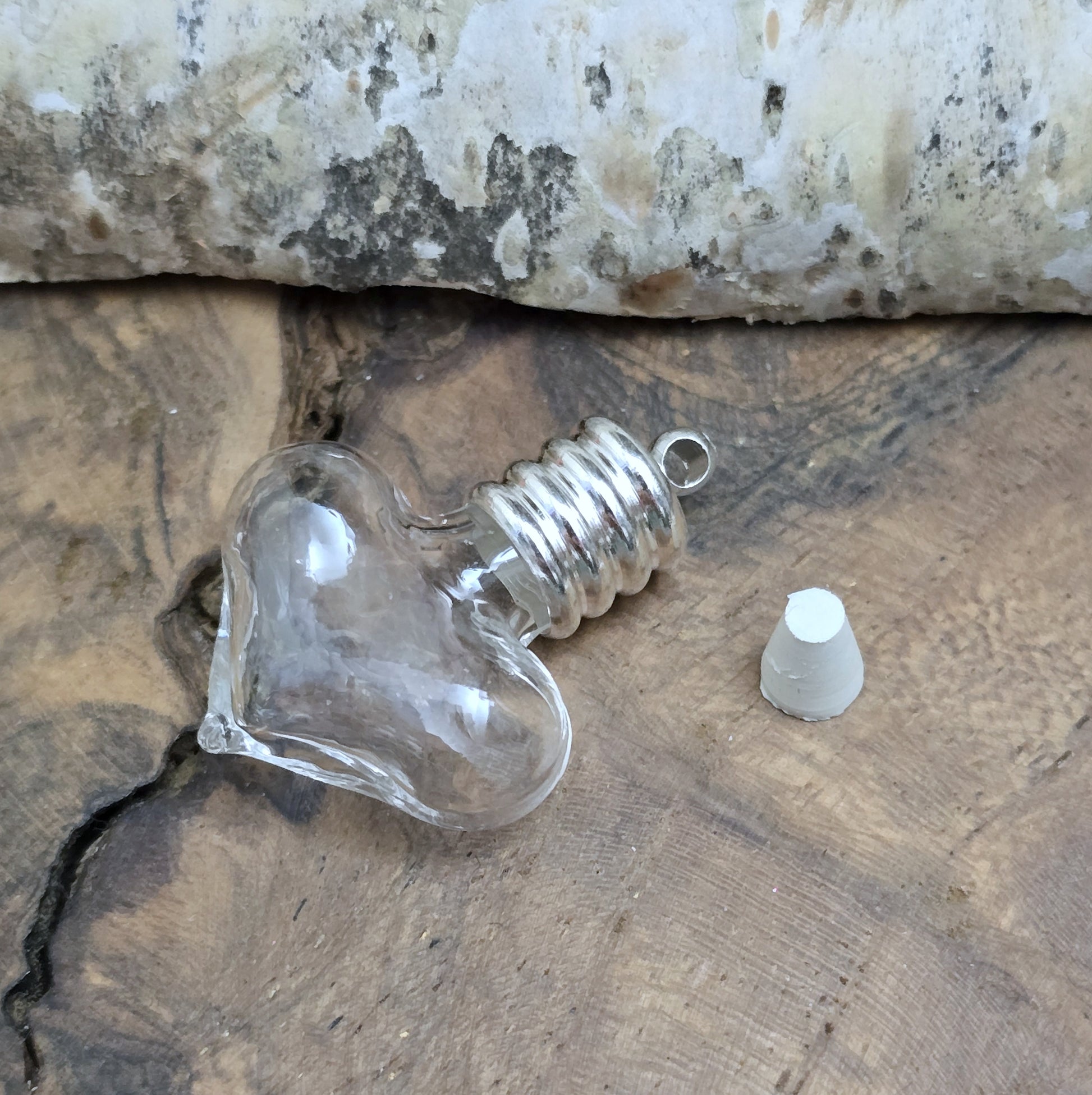 Kleiner Phiolenanhänger aus Glas, in Form eines Herzens mit silberfarbiger Kappe. Ideal zum Befüllen mit beschriftetem Reiskorn, Sand, Milchzahn, Asche, Haare udg.