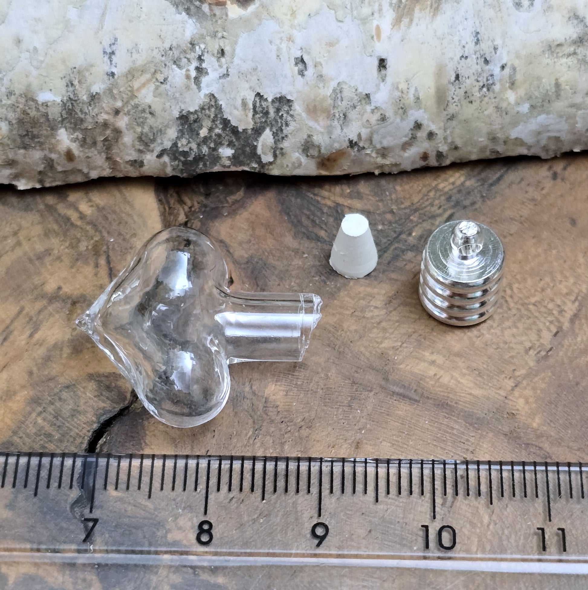 Kleiner Phiolenanhänger aus Glas, in Form eines Herzens mit silberfarbiger Kappe. Ideal zum Befüllen mit beschriftetem Reiskorn, Sand, Milchzahn, Asche, Haare udg.