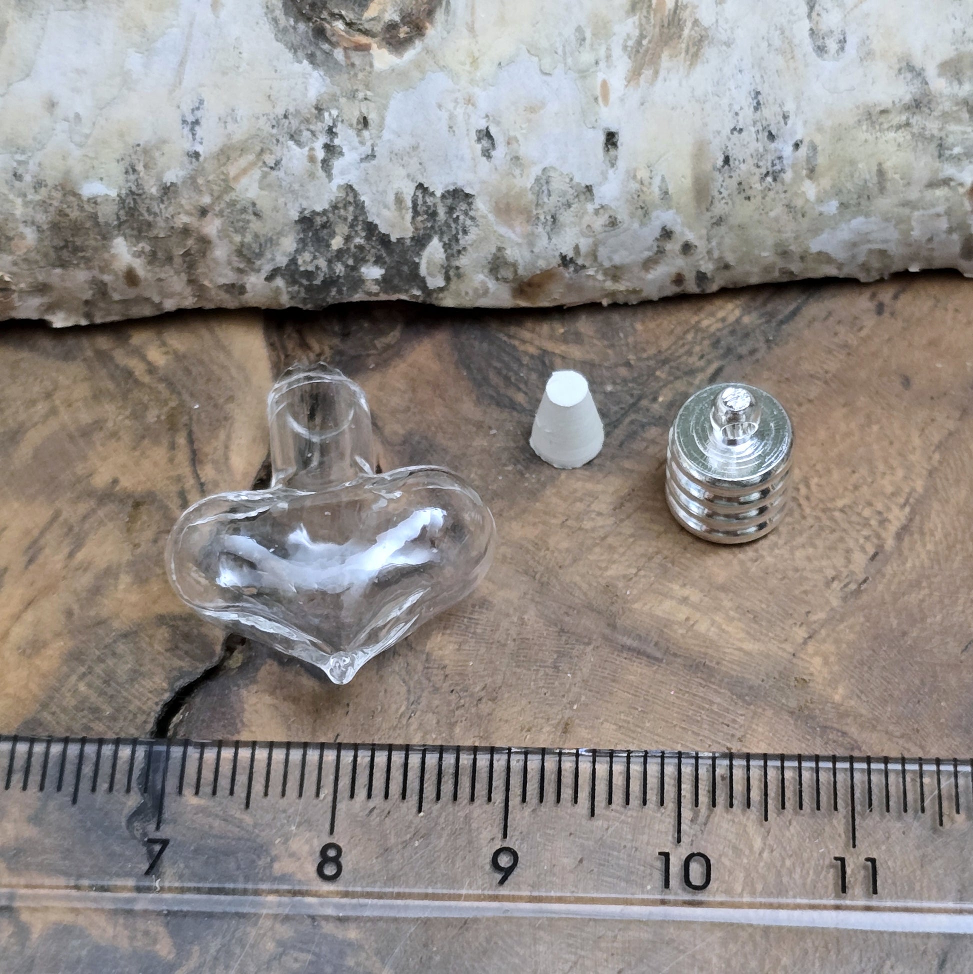 Kleiner Phiolenanhänger aus Glas, in Form eines Herzens mit silberfarbiger Kappe. Ideal zum Befüllen mit beschriftetem Reiskorn, Sand, Milchzahn, Asche, Haare udg.