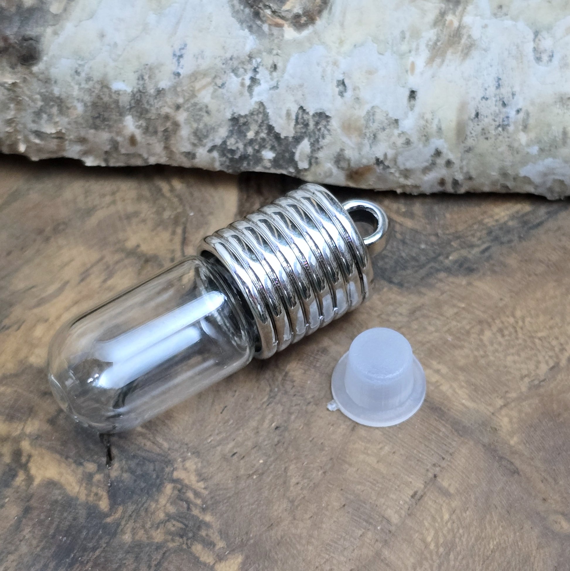 Anhänger Glasflasche mit rundem Boden zum selber befüllen.  Die Glasflasche hat oben eine "große" Öffnung und bietet Platz für eine Vielzahl von Erinnerungen und Materialien wie Edelsteinsplitter, Sand, Glitzer, Granulat, Tierhaare, Milchzähne, kleine Turmdeckelschnecken etc. (bitte beachten Sie die Öffnungsgröße). 
