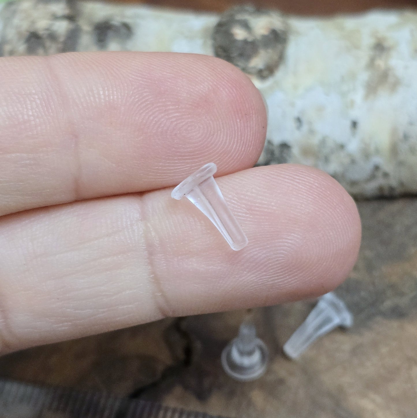 Silikonschutz für Ohrstecker auf einem Finger für Größenreferenz