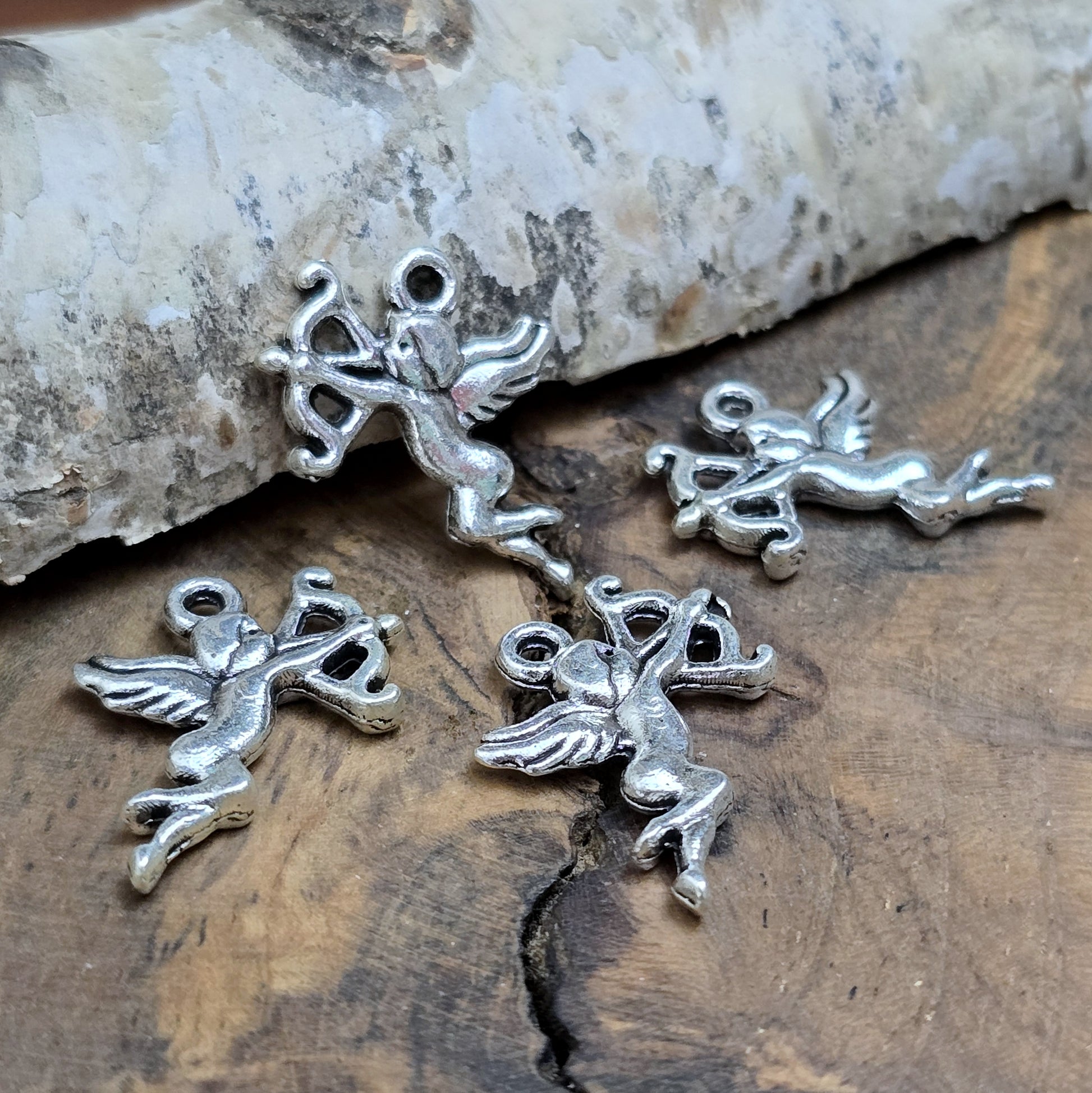 4 Charms Armor in antik silberfarbig liegend auf einem Brett aus Holz