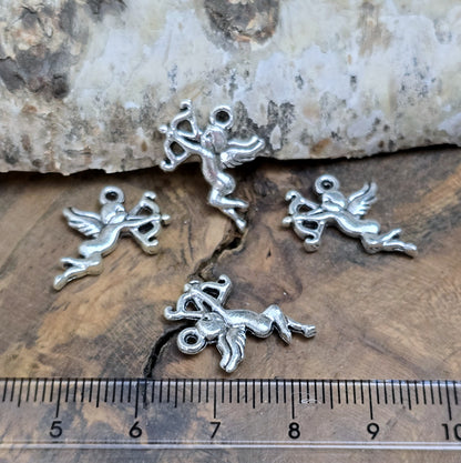 4 Charms Armor in antik silberfarbig liegend auf einem Holzbrett mit einem Lineal für einen besseren Größenvergleich
