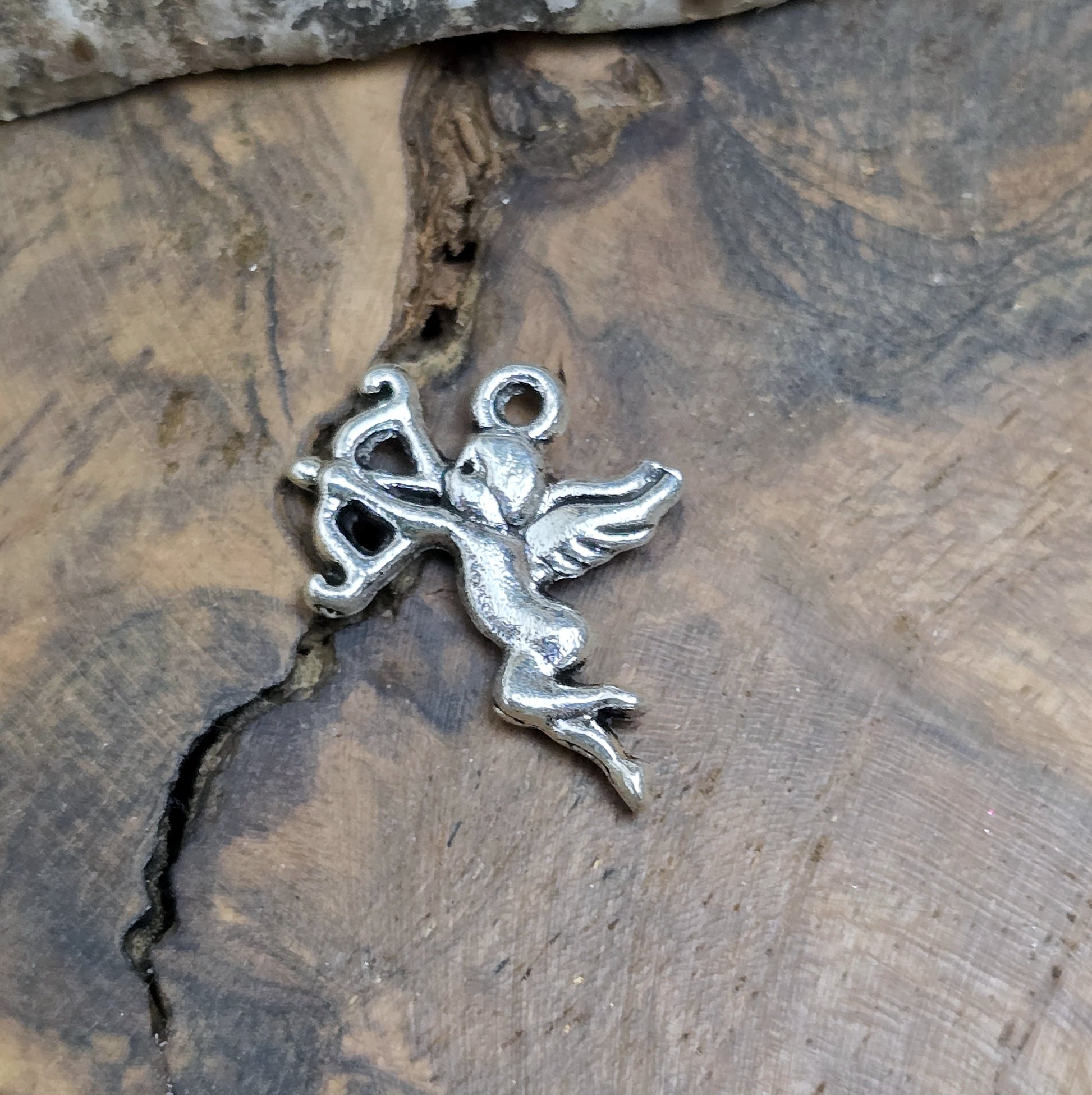 Ein kleiner Anhänger Armor in antikem silber liegend auf einem Holzbrett