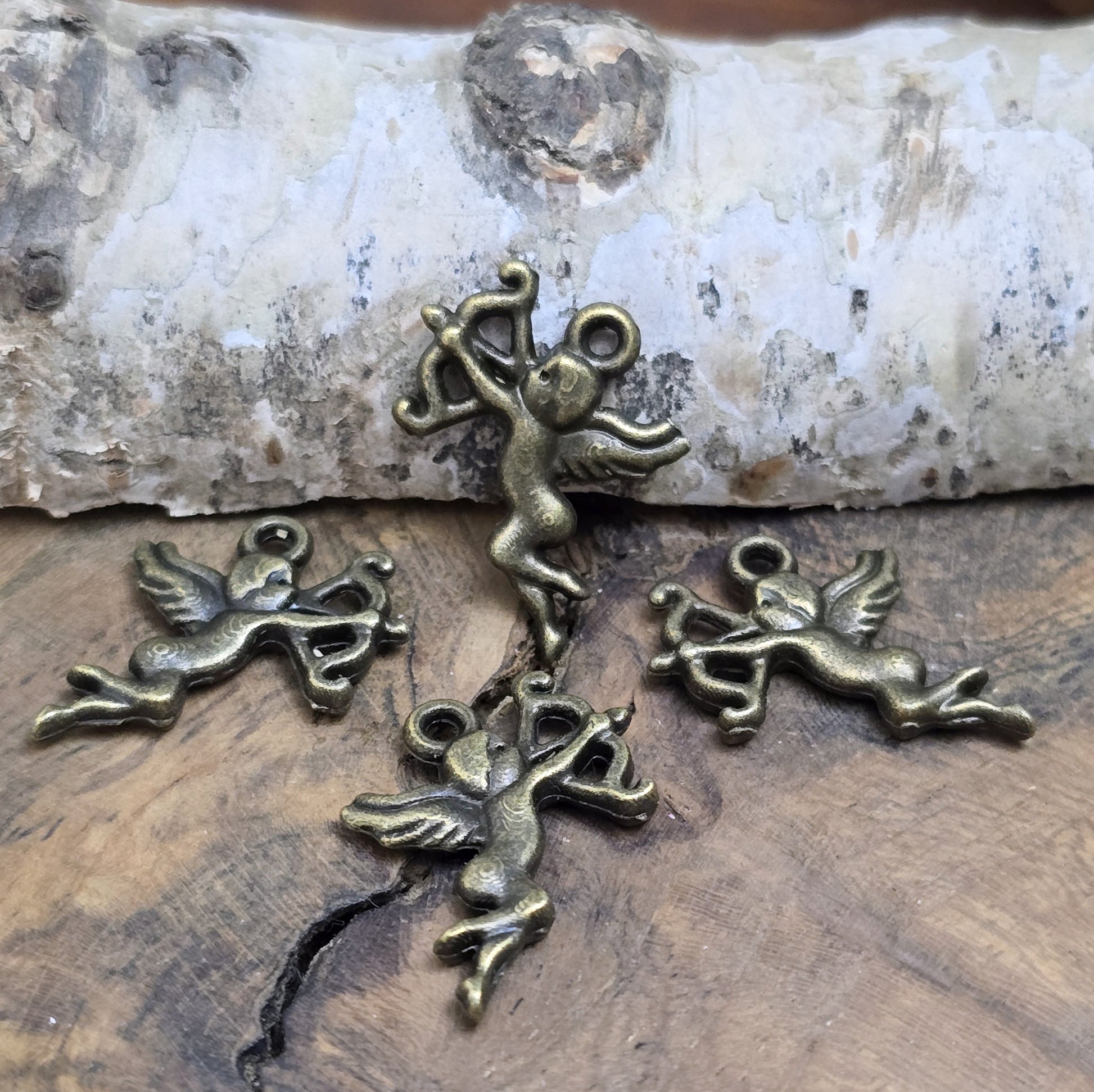 4 Charms Armor in antik bronzefarben liegend auf einem Holzbrett 