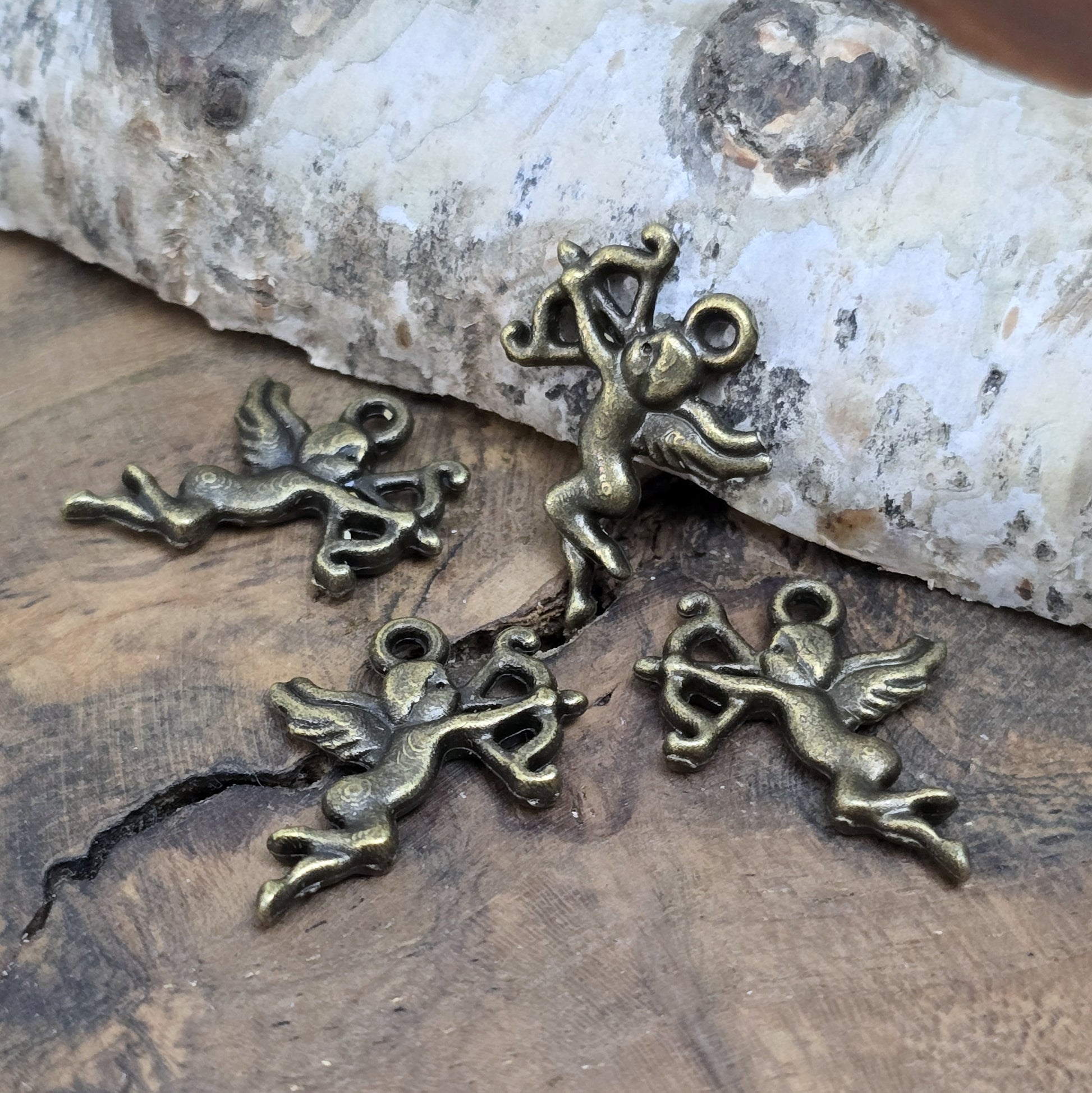 4 Charms Armor in antik bronzefarben liegend auf einem Holzbrett nochmal aus einer anderen Perspektive