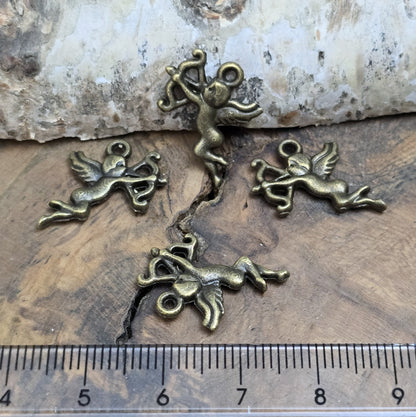 4 Charms Armor in antik bronzefarben liegend auf einem Holzbrett  mit einem Lineal für einen besseren Größenvergleich