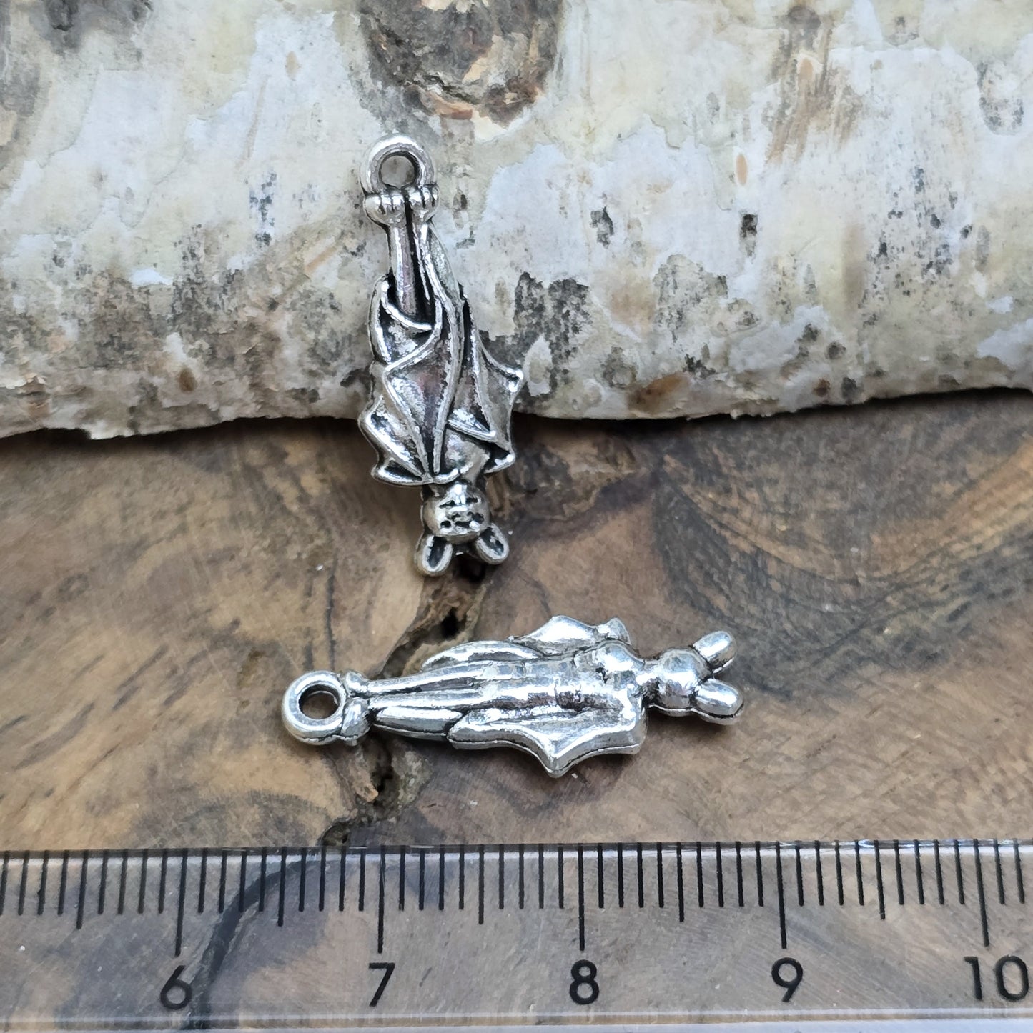 2 antik silberne Charms, hängende Fledermaus in Detailansicht, mit Lineal zur besseren Größenübersicht