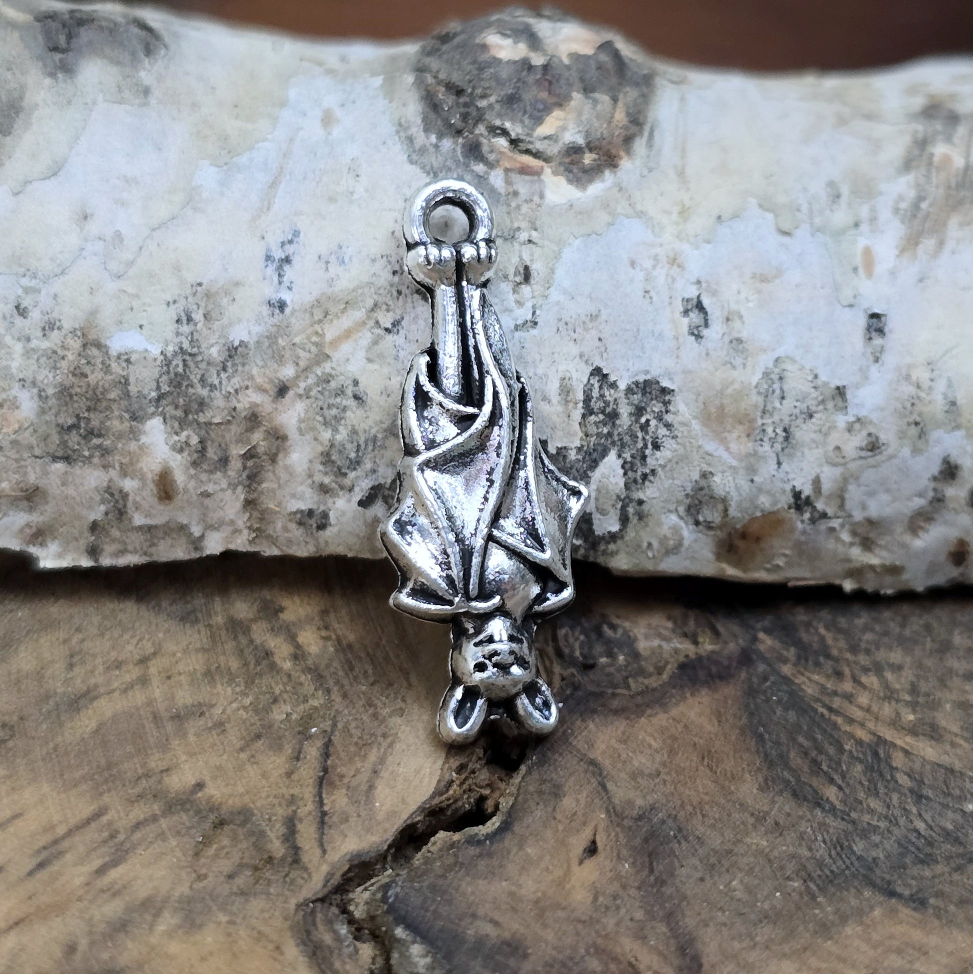 Einzelner antik silberner Charm, hängende Fledermaus in Nahaufnahme.