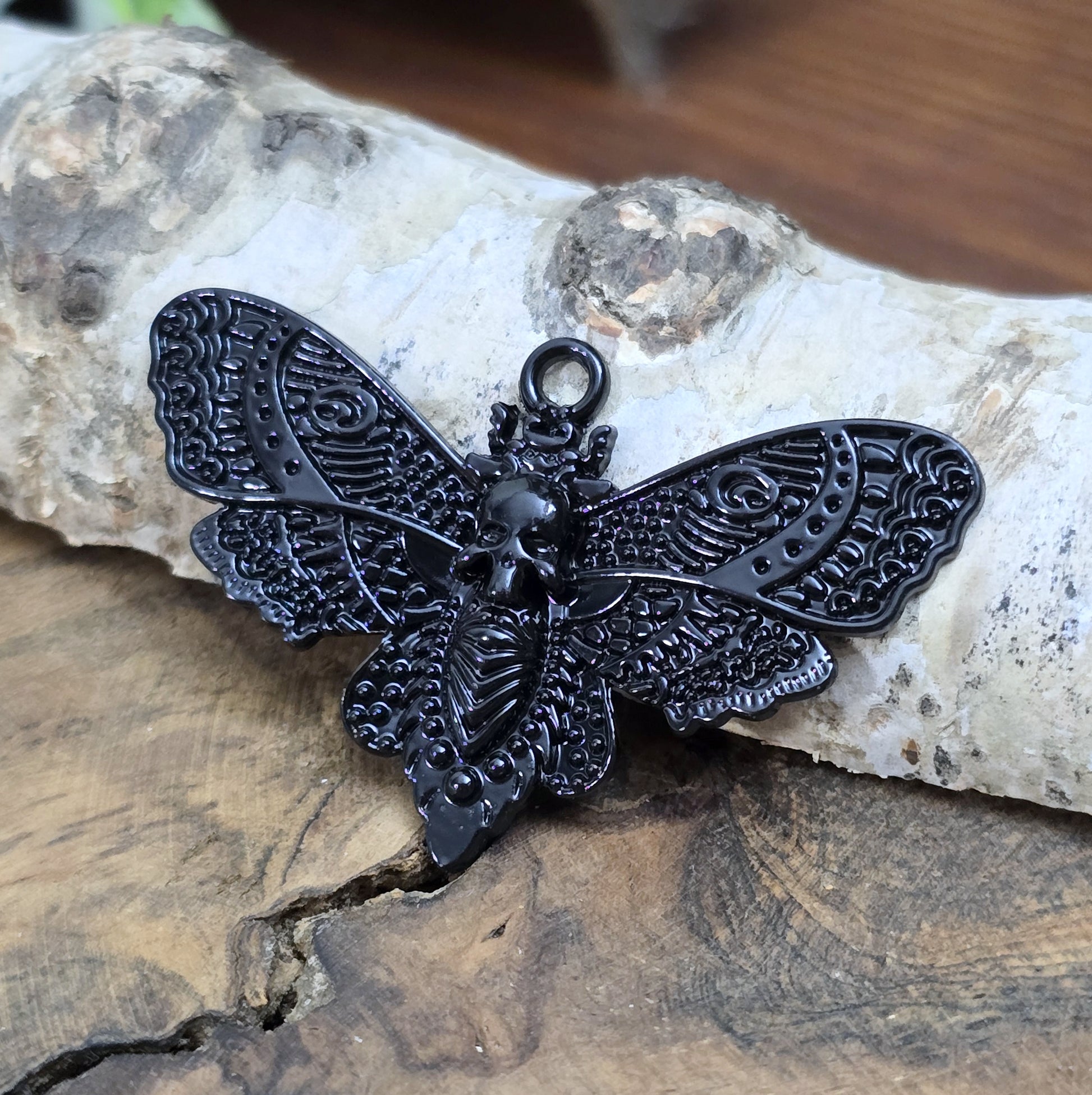 Das Bild zeigt einen Anhänger mit schwarzer Beschichtung. Mit 27 mm Breite und einer stabilen Öse eignet er sich perfekt für Ketten, Choker und andere individuelle Schmuckstücke.