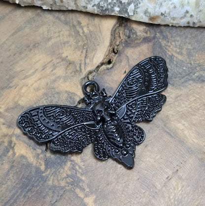 Das Bild zeigt einen Anhänger mit schwarzer Beschichtung. Mit 27 mm Breite und einer stabilen Öse eignet er sich perfekt für Ketten, Choker und andere individuelle Schmuckstücke.