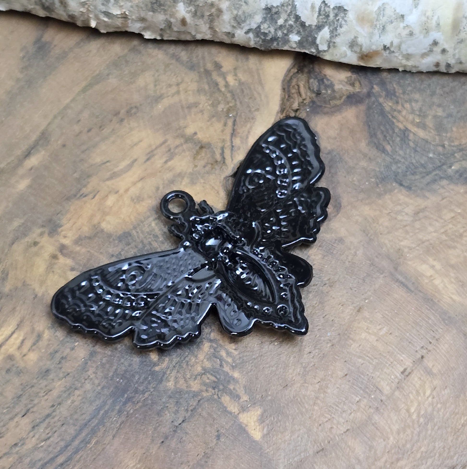 Das Bild zeigt einen Anhänger mit schwarzer Beschichtung. Mit 27 mm Breite und einer stabilen Öse eignet er sich perfekt für Ketten, Choker und andere individuelle Schmuckstücke.